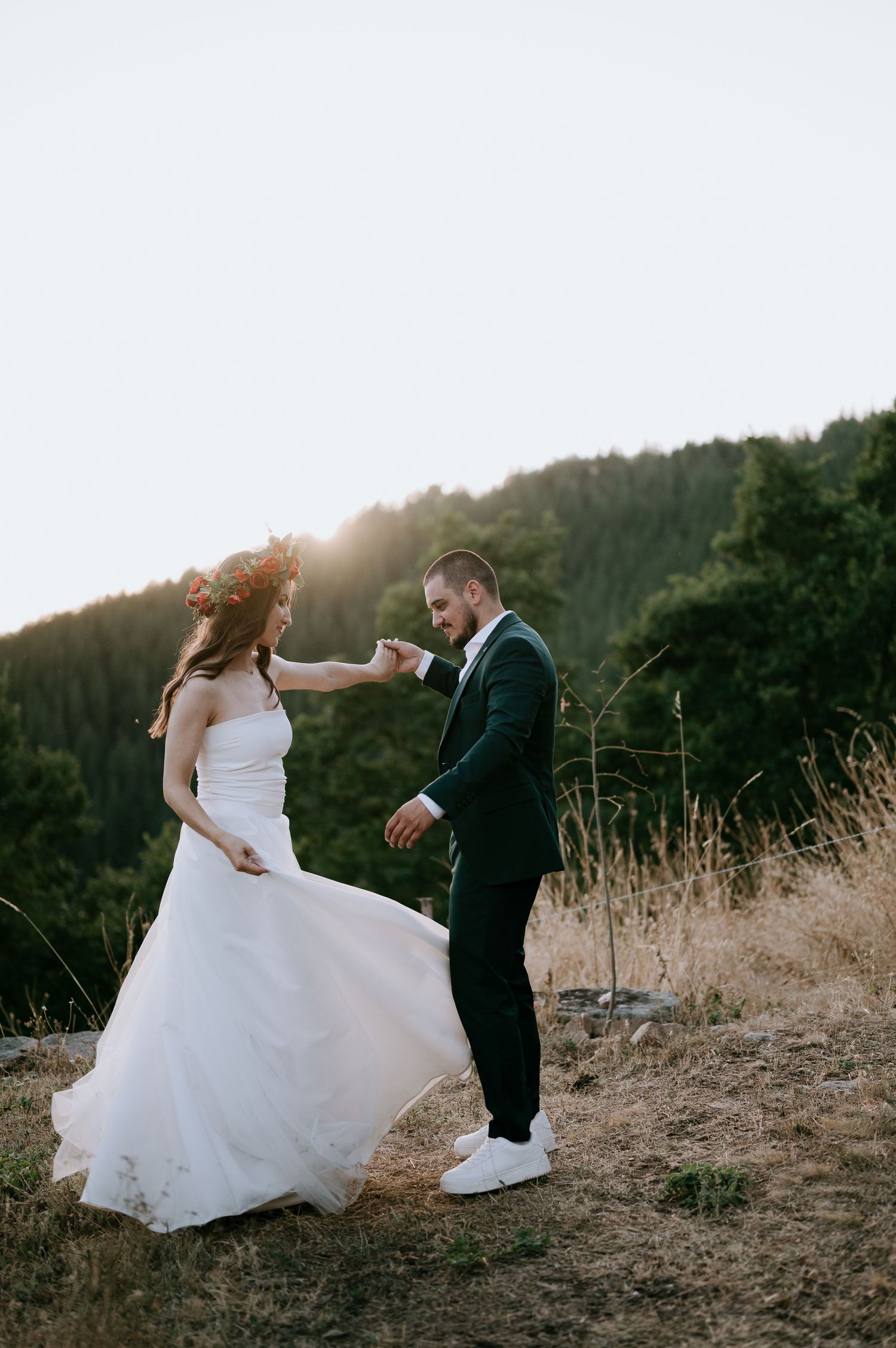 A couple dances playfully on a mountainside during their sunset wedding photoshoot.