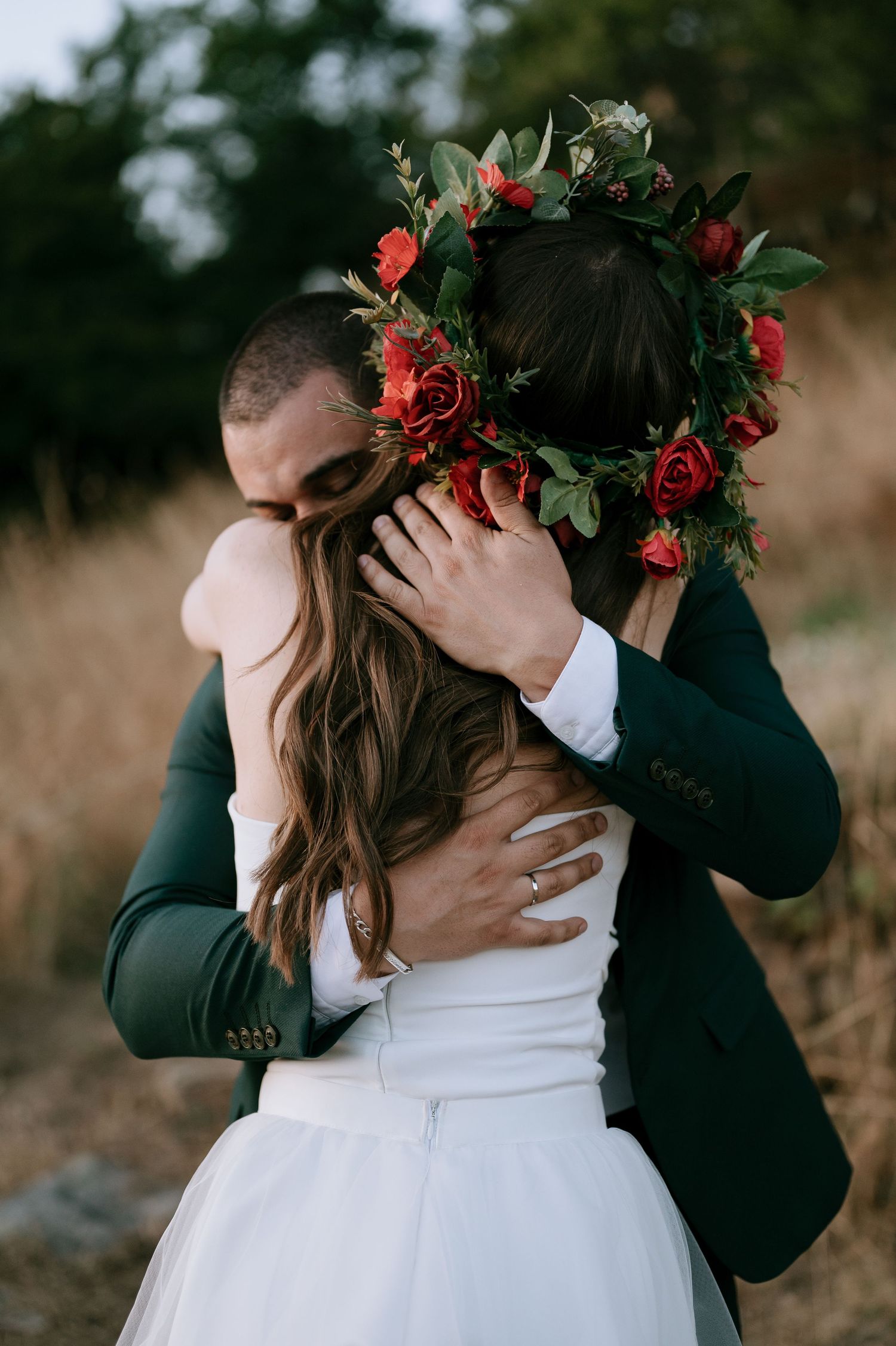 Romantic embrace between newlyweds with red rose crown details.