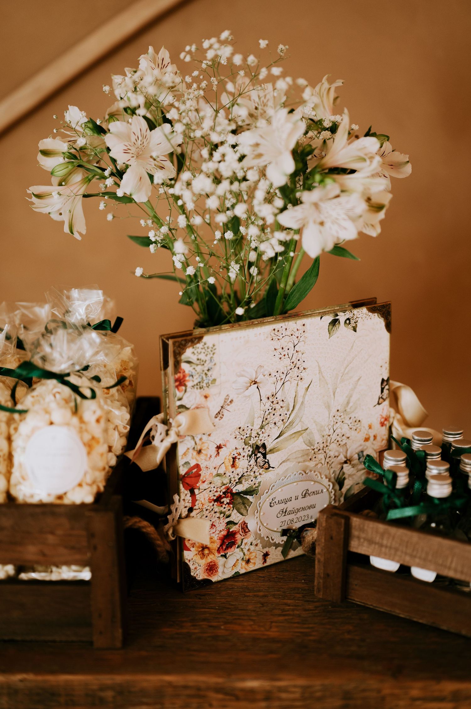White floral arrangement with decorative book and wooden boxes on dark wooden surface.