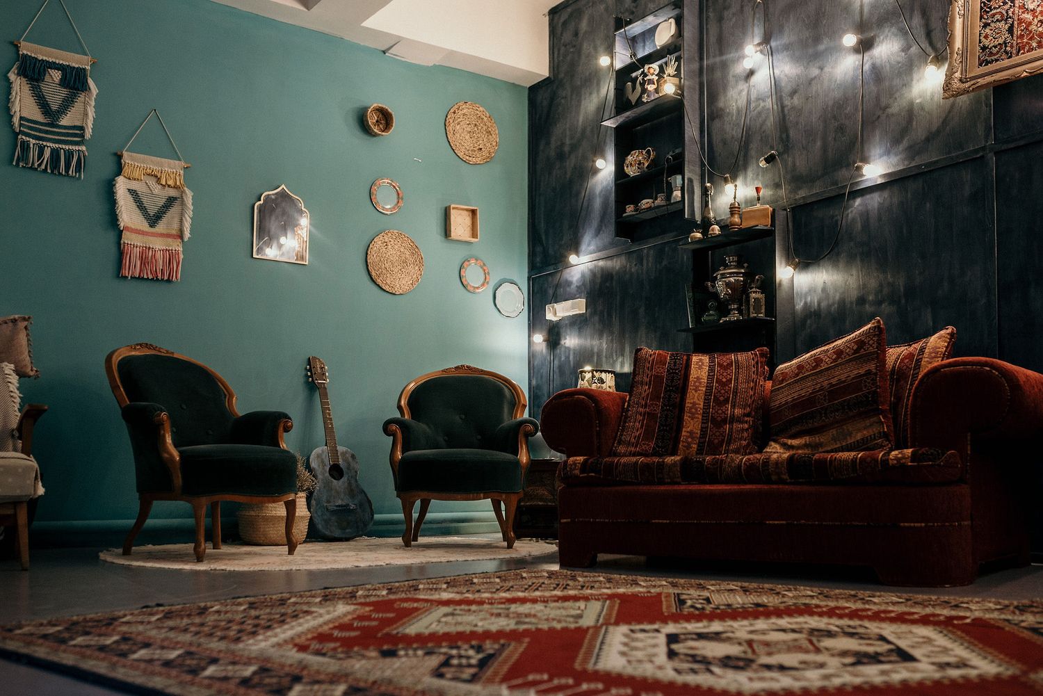 Cozy living room with teal walls, vintage chairs, and decorative wall art.