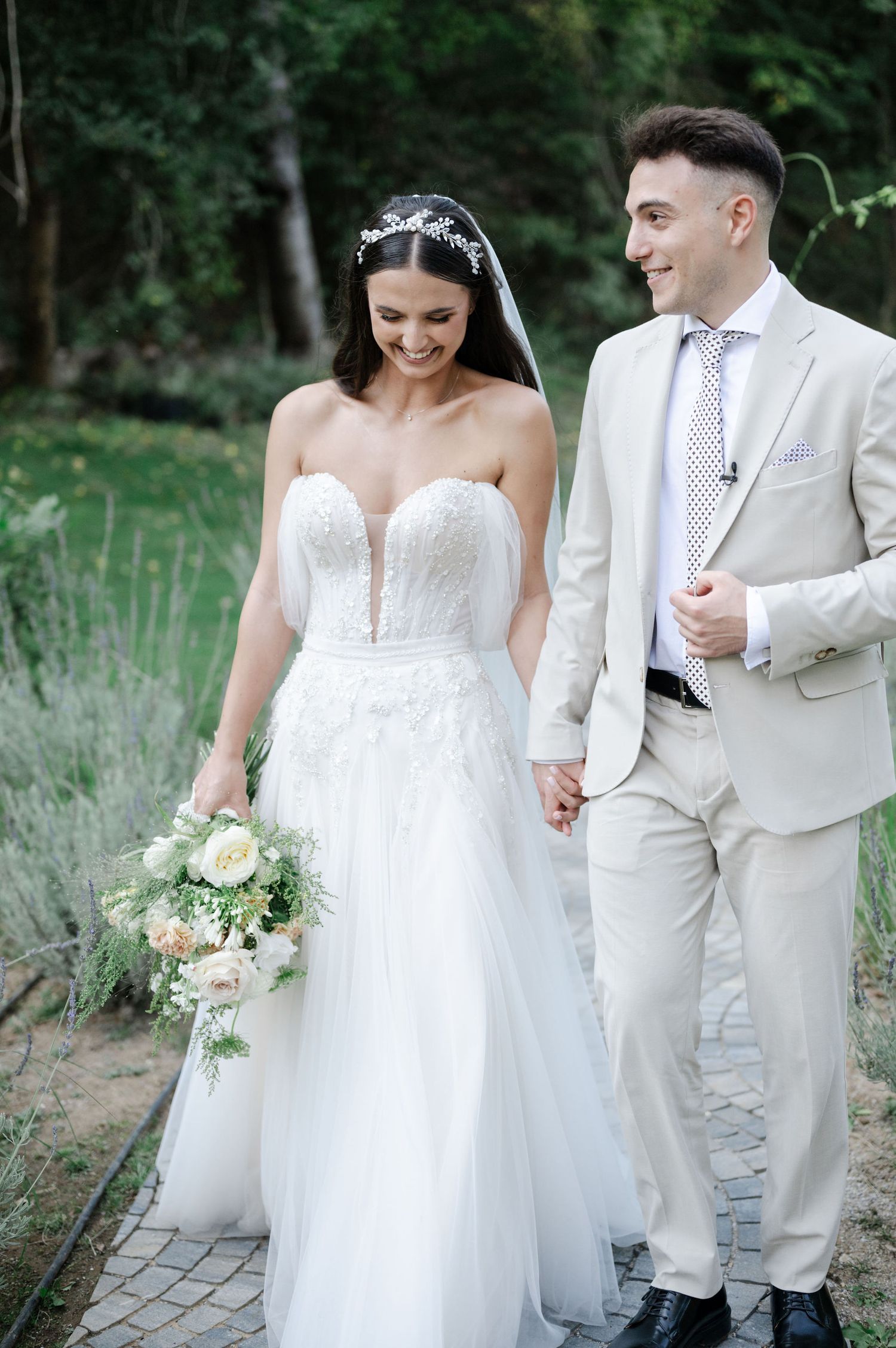 Romantic wedding portrait in garden setting with couple in white formal attire.