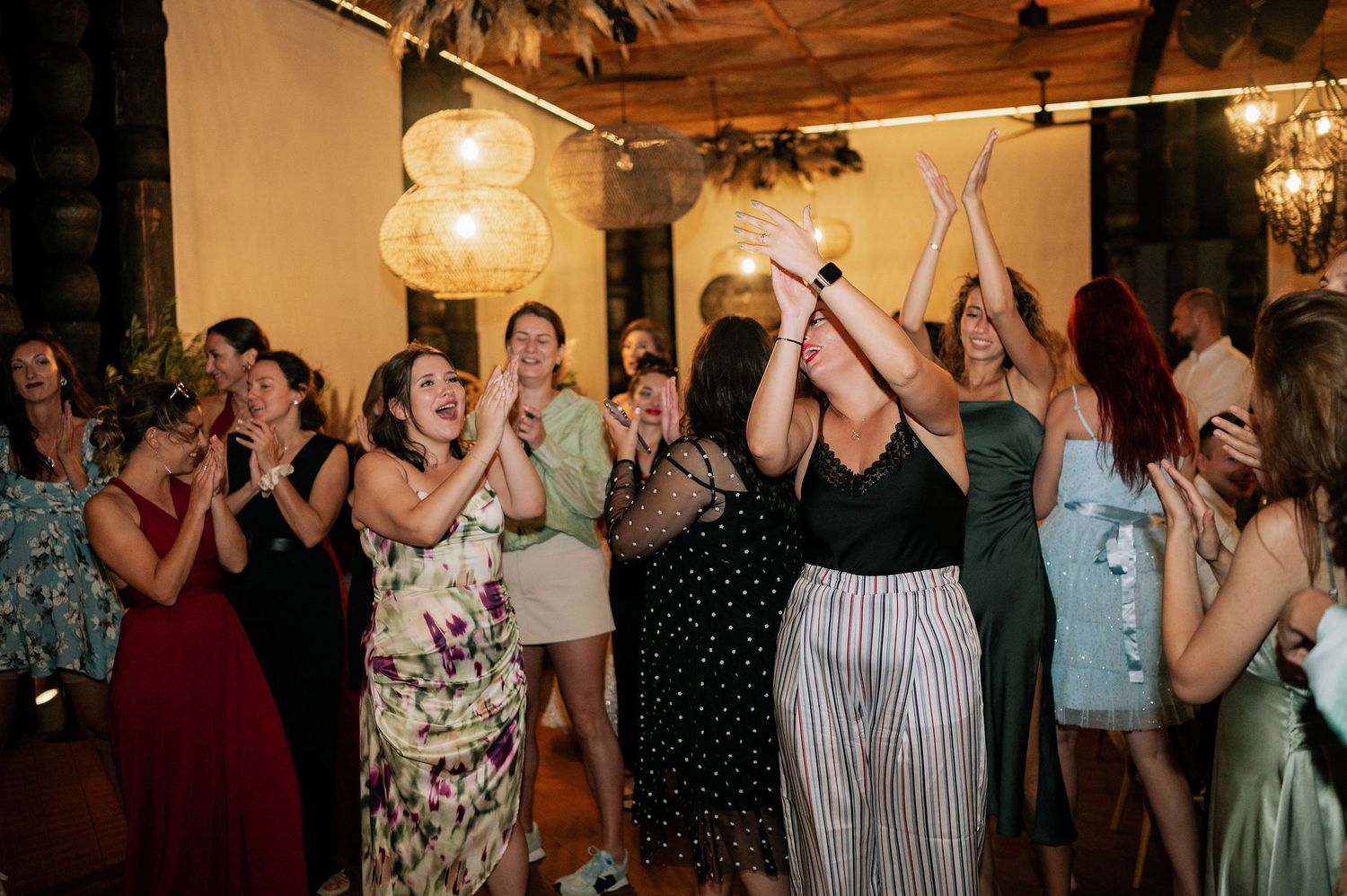 Wedding guests dancing and celebrating on the dance floor under warm lighting.