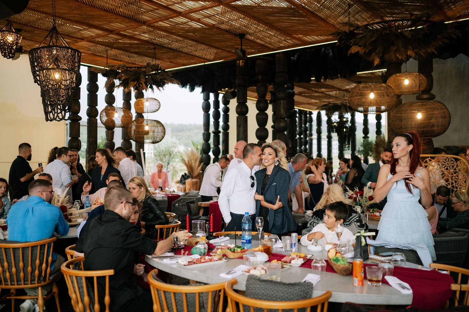 Wedding reception guests gathered in a rustic venue with wooden beams and ornate pillars.