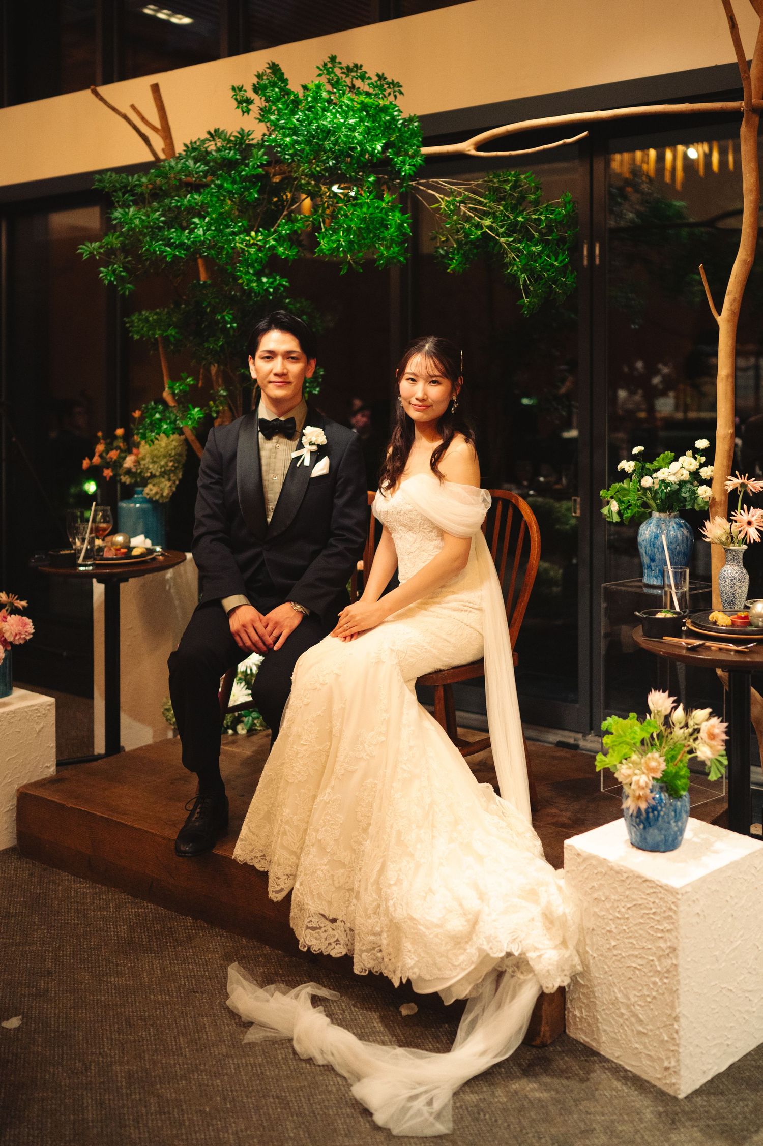 A wedding couple poses for photos under a glowing green tree installation.