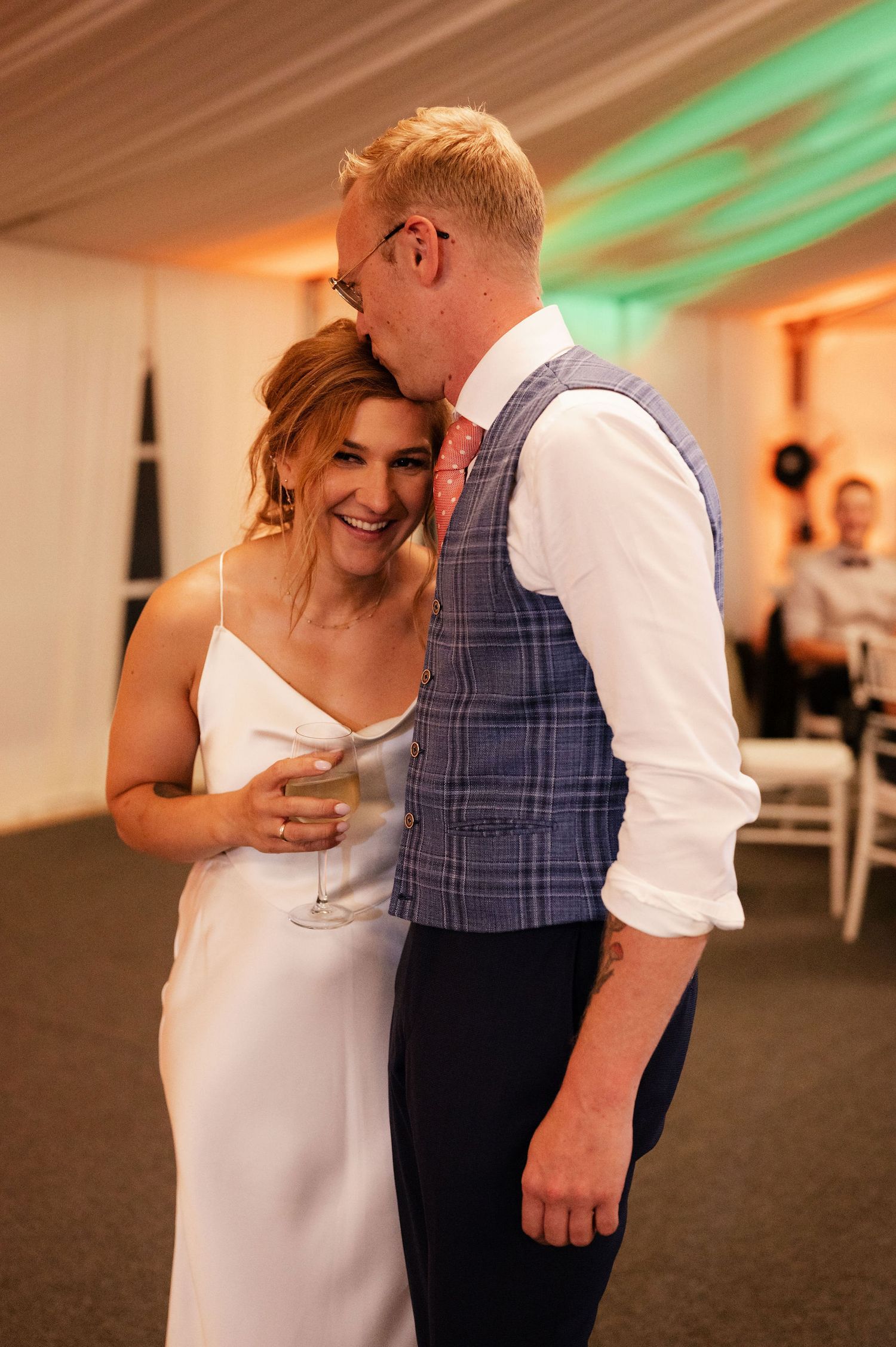 A couple shares an intimate moment during their wedding reception while holding champagne glasses.