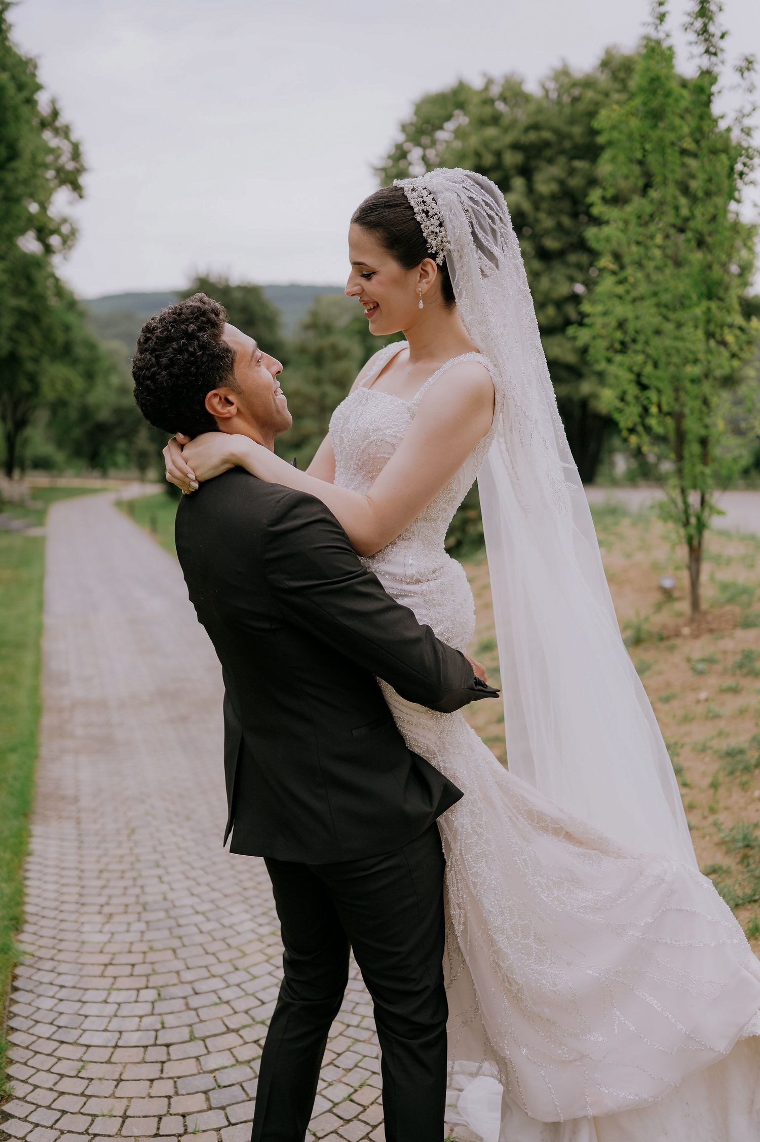 A playful wedding photoshoot sequence showing a couple dancing and twirling on a brick pathway surrounded by greenery.
