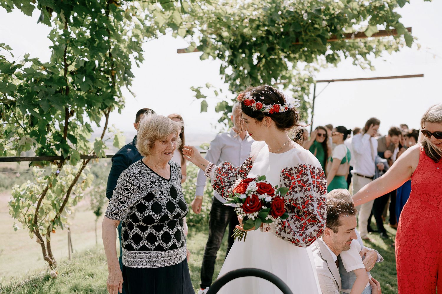 Outdoor wedding celebration with guests mingling under lush greenery.