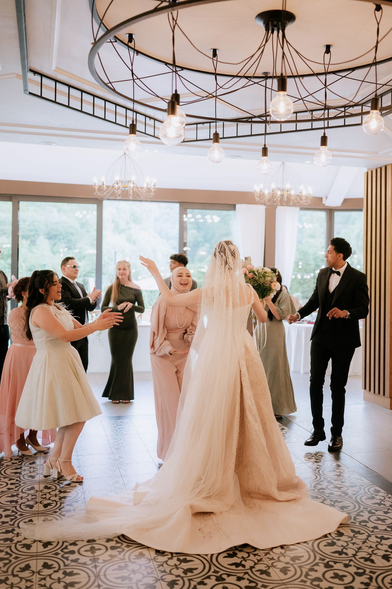 Wedding party celebrating in a modern venue with patterned floor and industrial lighting.