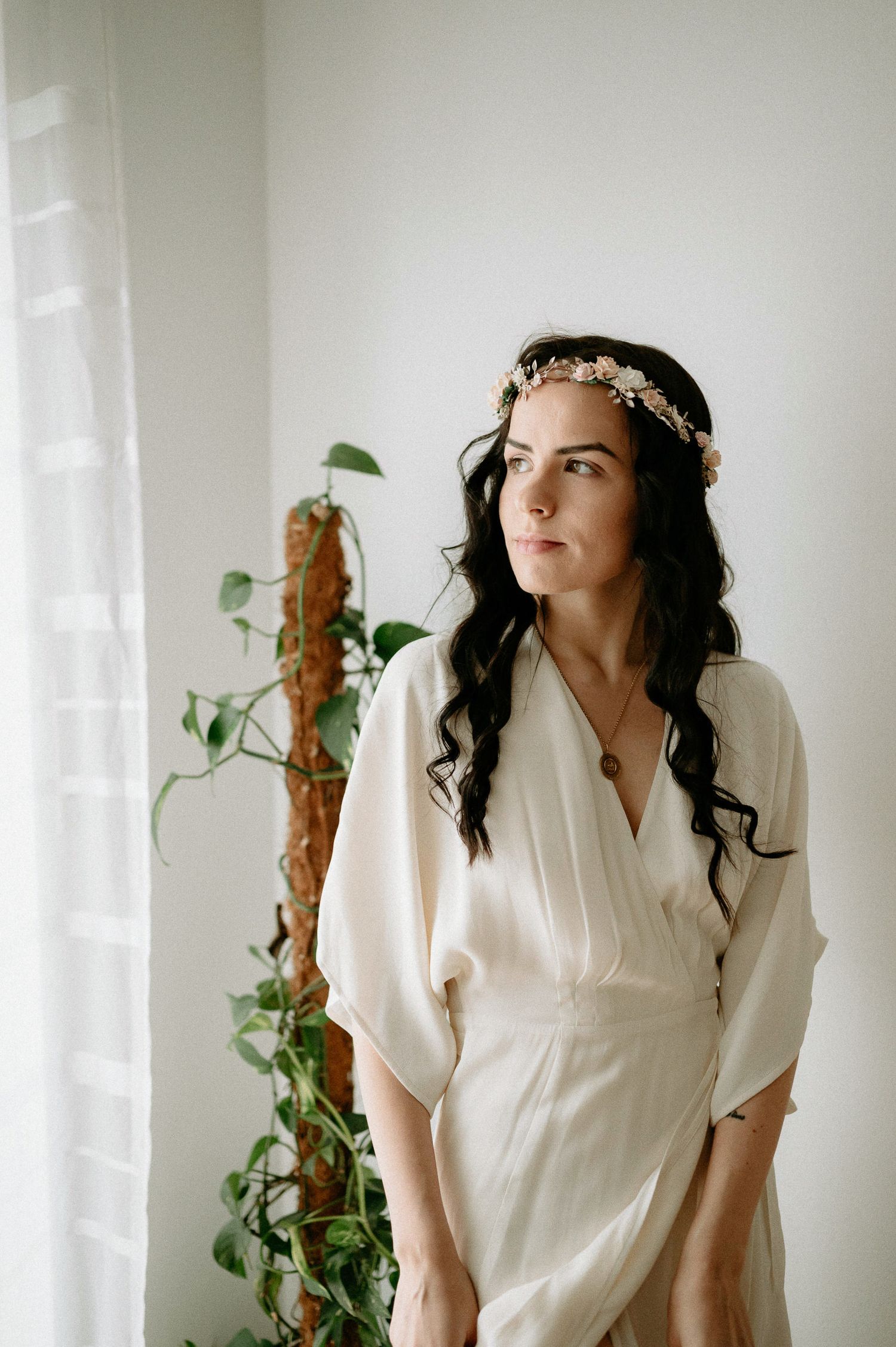 Elegant portrait with climbing vines and natural window light creating a romantic atmosphere.