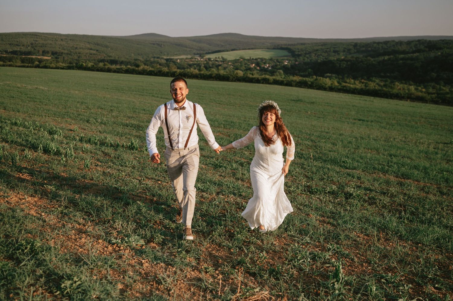 A couple explores a scenic hillside meadow during their countryside wedding celebration.