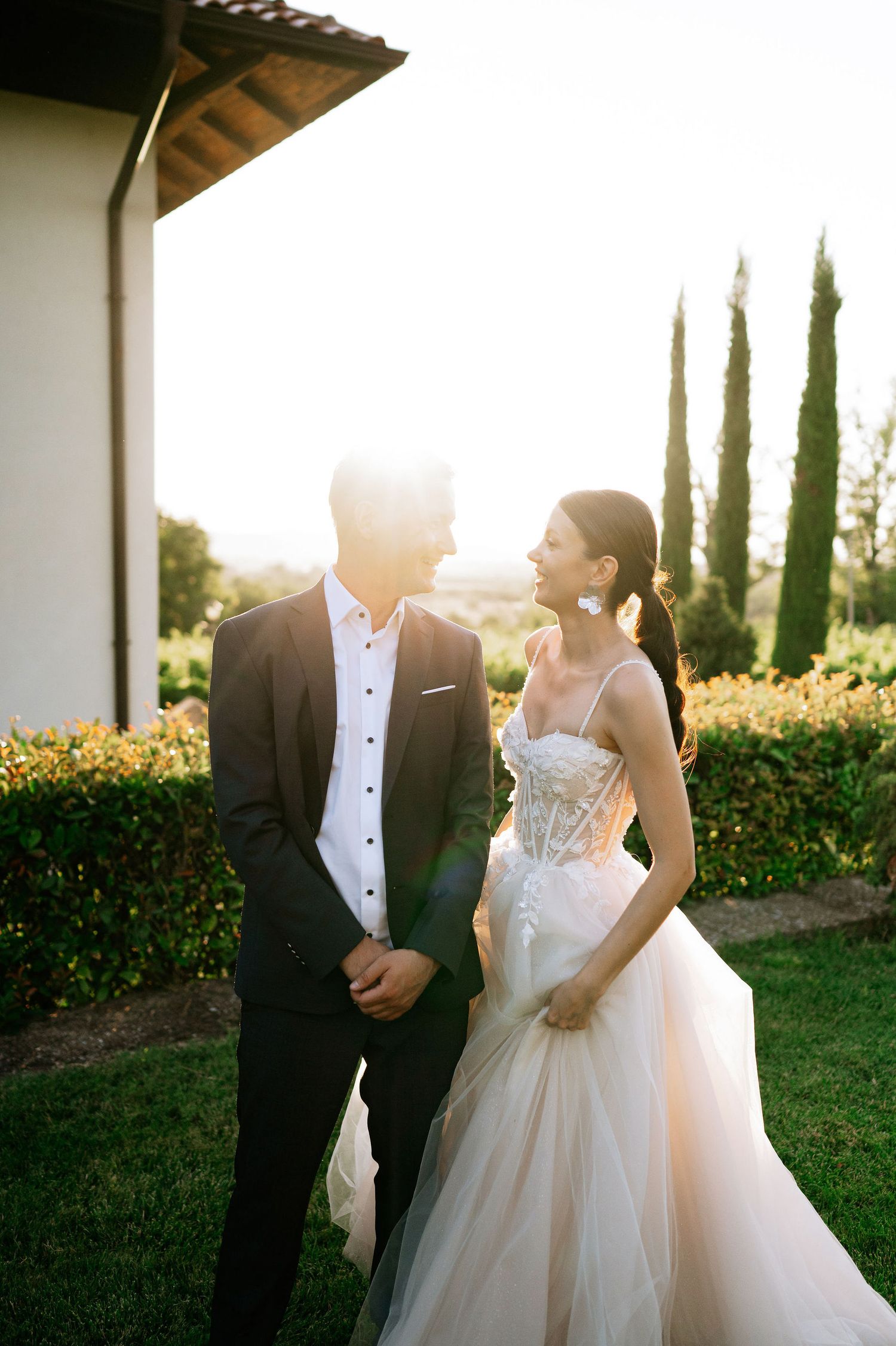 Elegant wedding couple shares a romantic moment dancing in a garden setting at sunset.