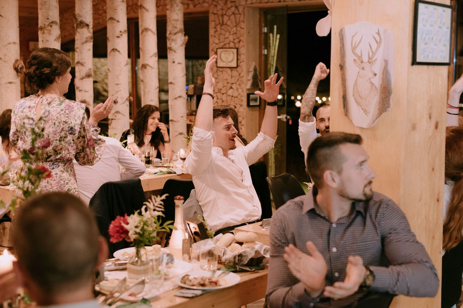 Wedding party dancing and mingling at an indoor reception with warm lighting.