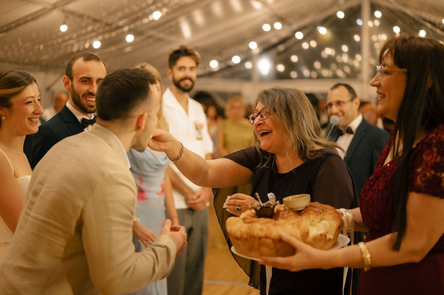 Candid moments of guests laughing and enjoying themselves at an indoor wedding reception with warm lighting.