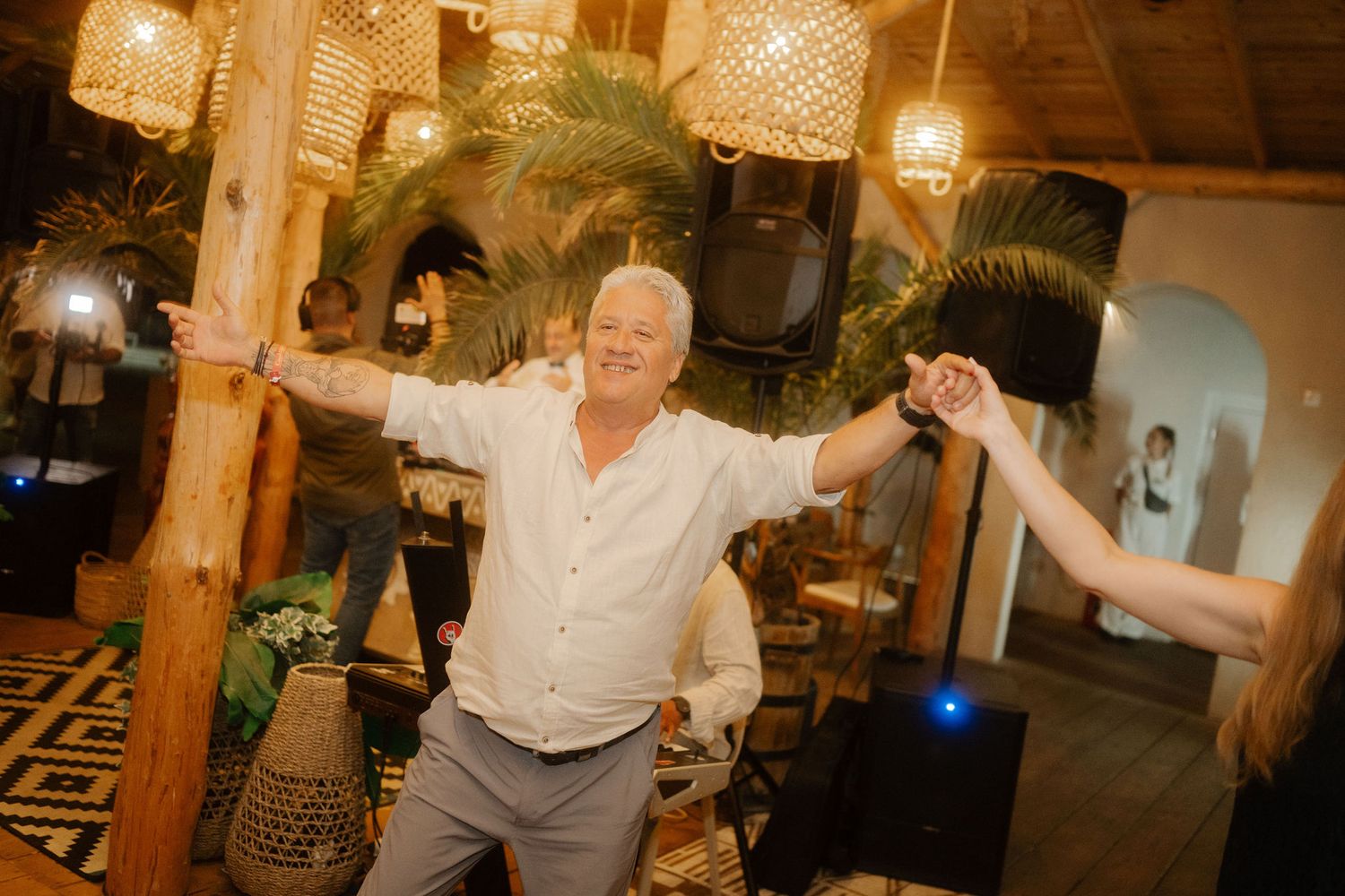 People dancing and celebrating at a warmly lit indoor reception venue with a festive atmosphere.