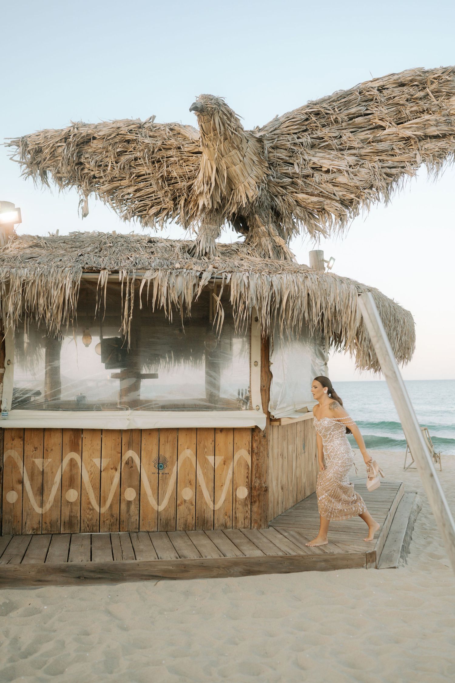 A sequence of photos showing a dog jumping and playing at a rustic beach bar with thatched roof at sunset.