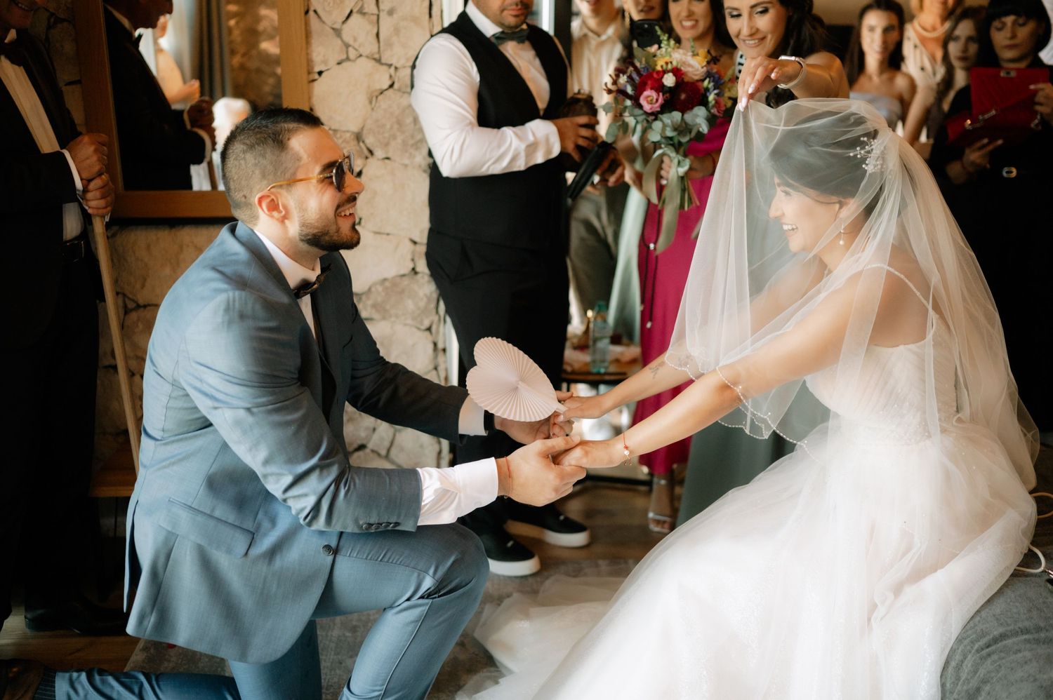 A couple shares an intimate moment during their wedding ceremony as they exchange rings in a rustic indoor venue.