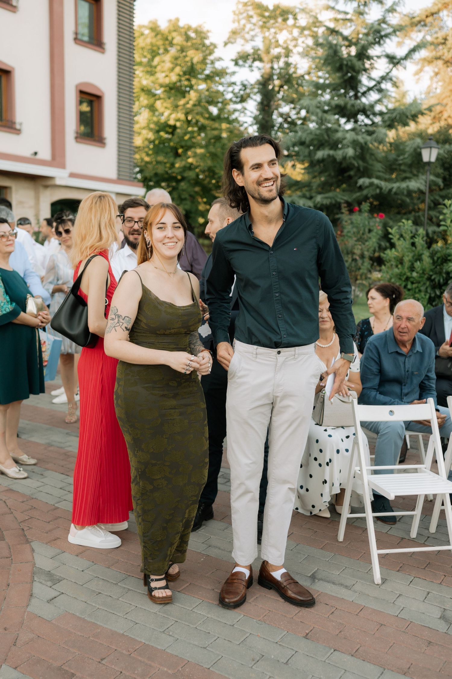 Group of people dancing and socializing at an outdoor event on a brick patio during golden hour.