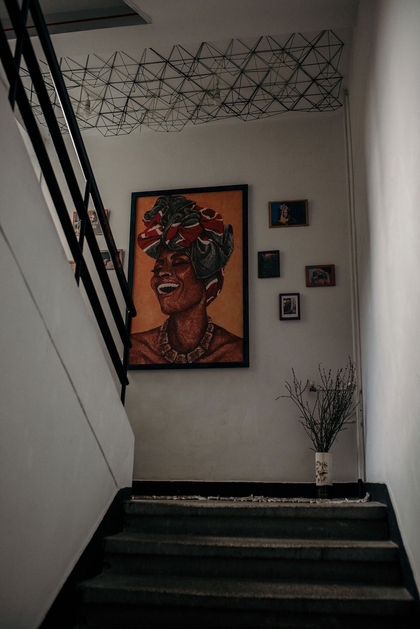 White interior space with geometric ceiling detail and colorful wall art featuring vibrant portraits.