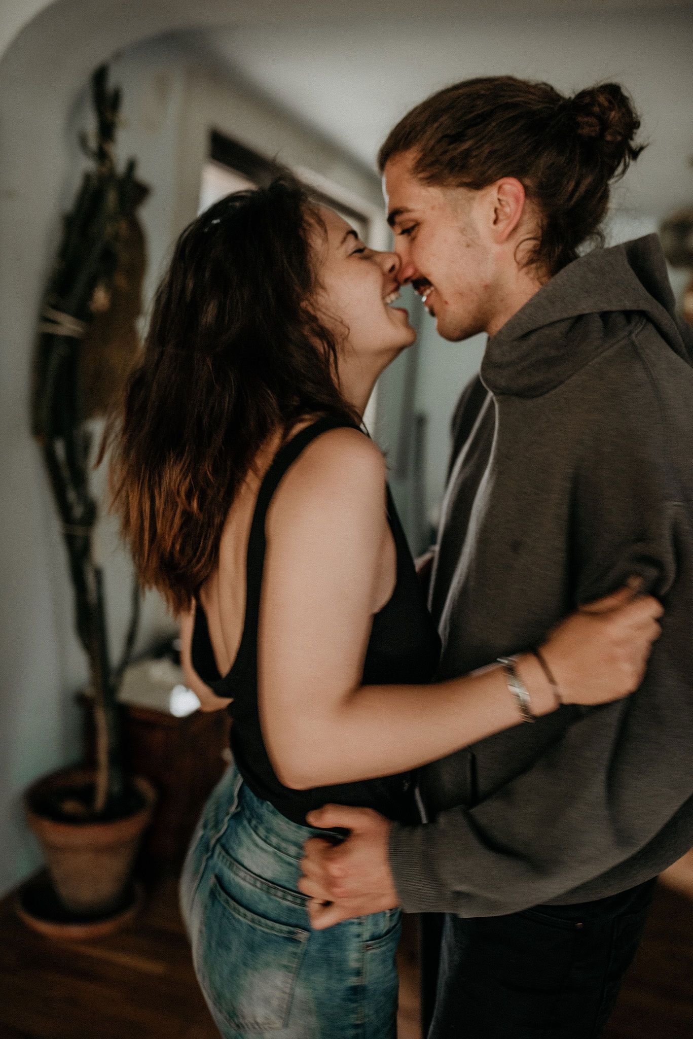 A romantic couple shares an intimate moment in a dimly lit room while wearing casual clothing.
