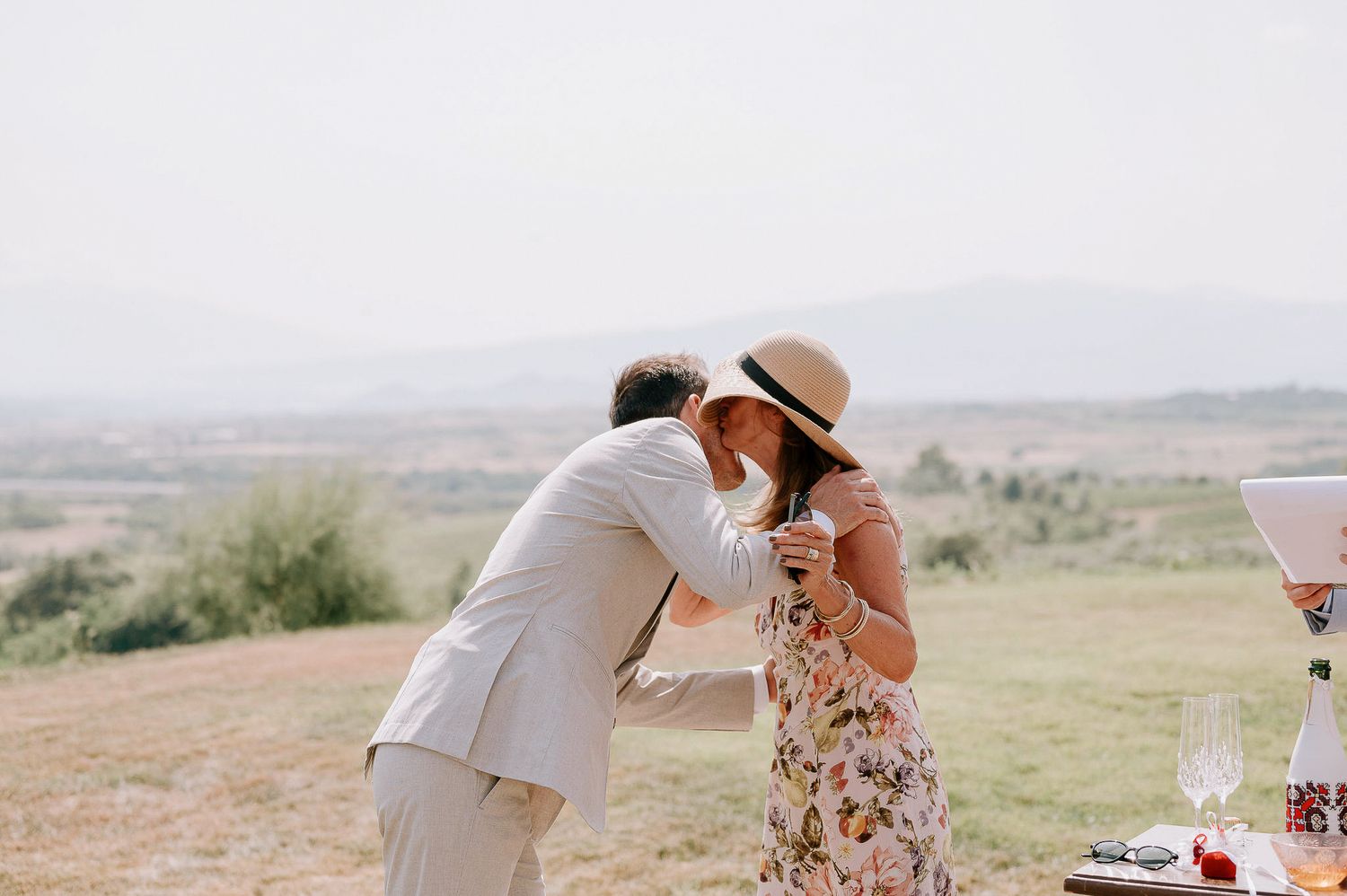 Wedding guests celebrate at an outdoor reception in a scenic hillside location.