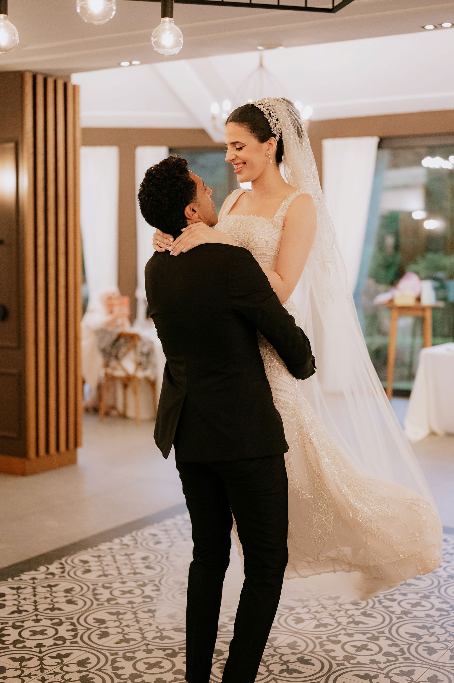 A romantic dance lift captured during a wedding reception in an elegant venue with patterned floors.