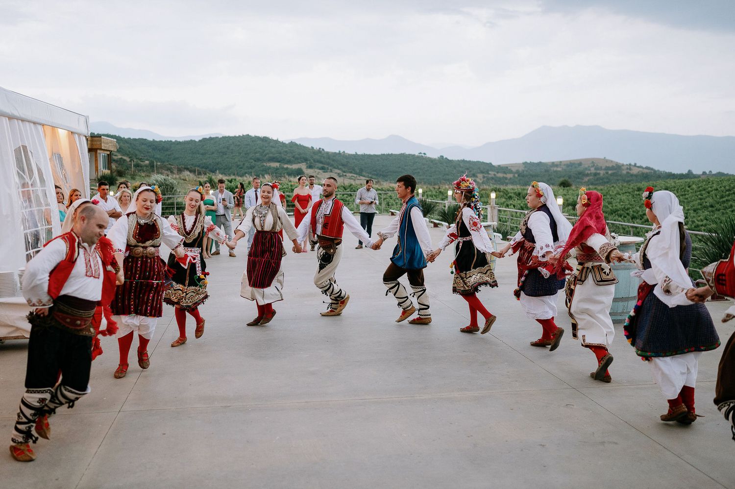 Folk dancers in traditional costumes perform a synchronized dance routine outdoors.
