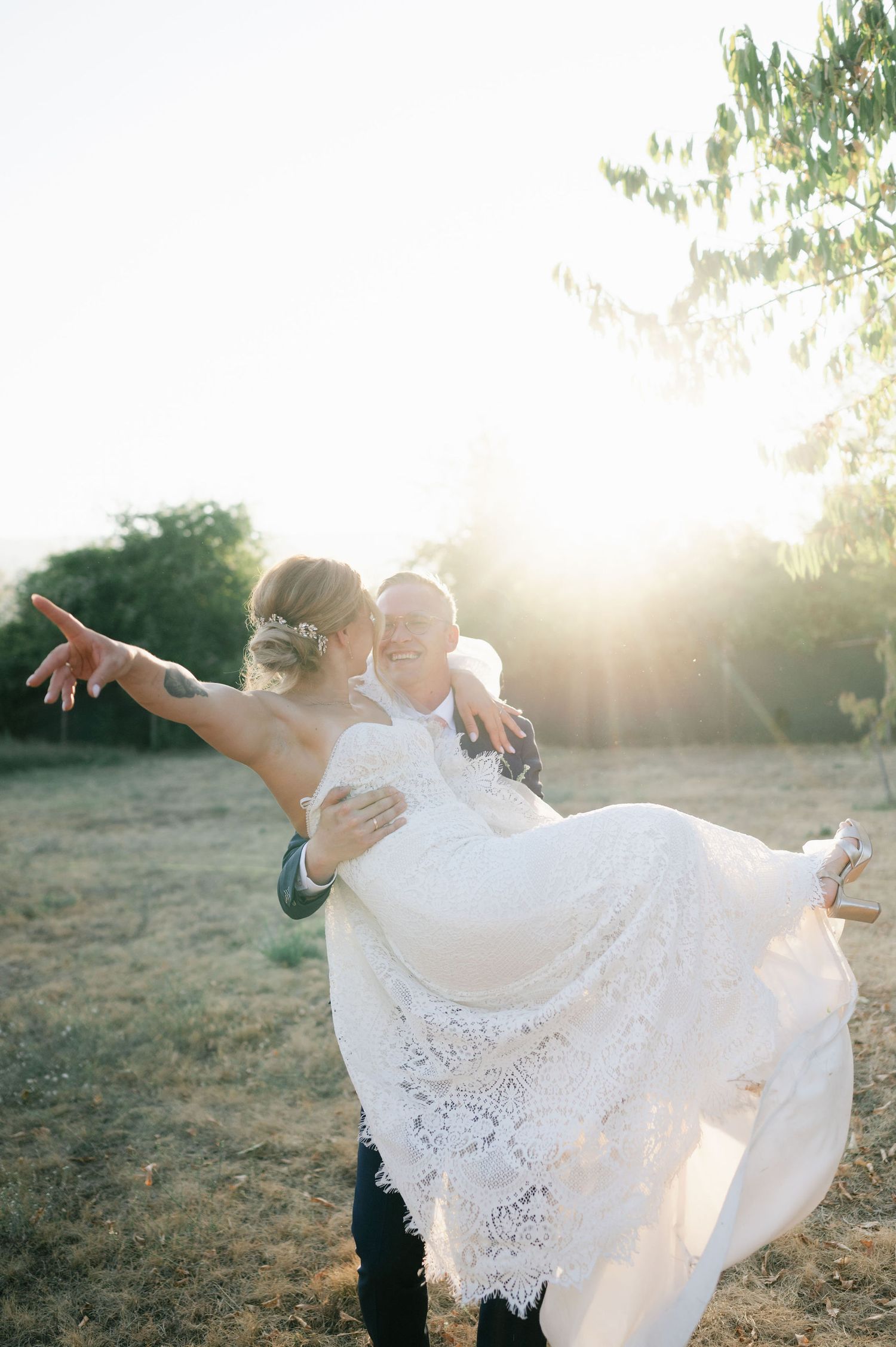 Joyful wedding dance captured against setting sun with bride's dress billowing dramatically.
