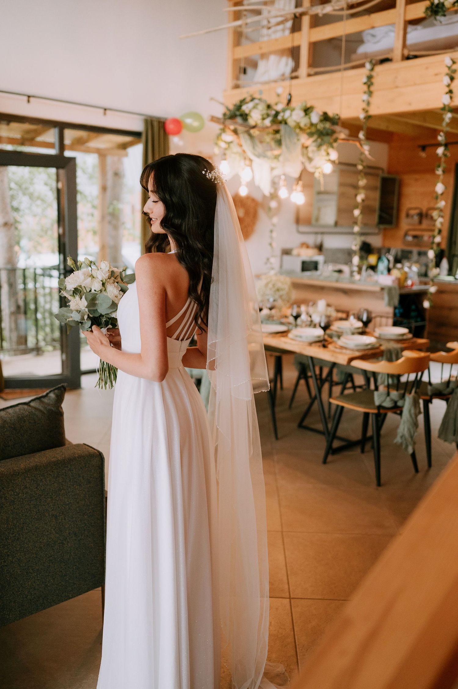 A wedding venue interior with wooden walls and string lights features elegant table settings and floral decor.