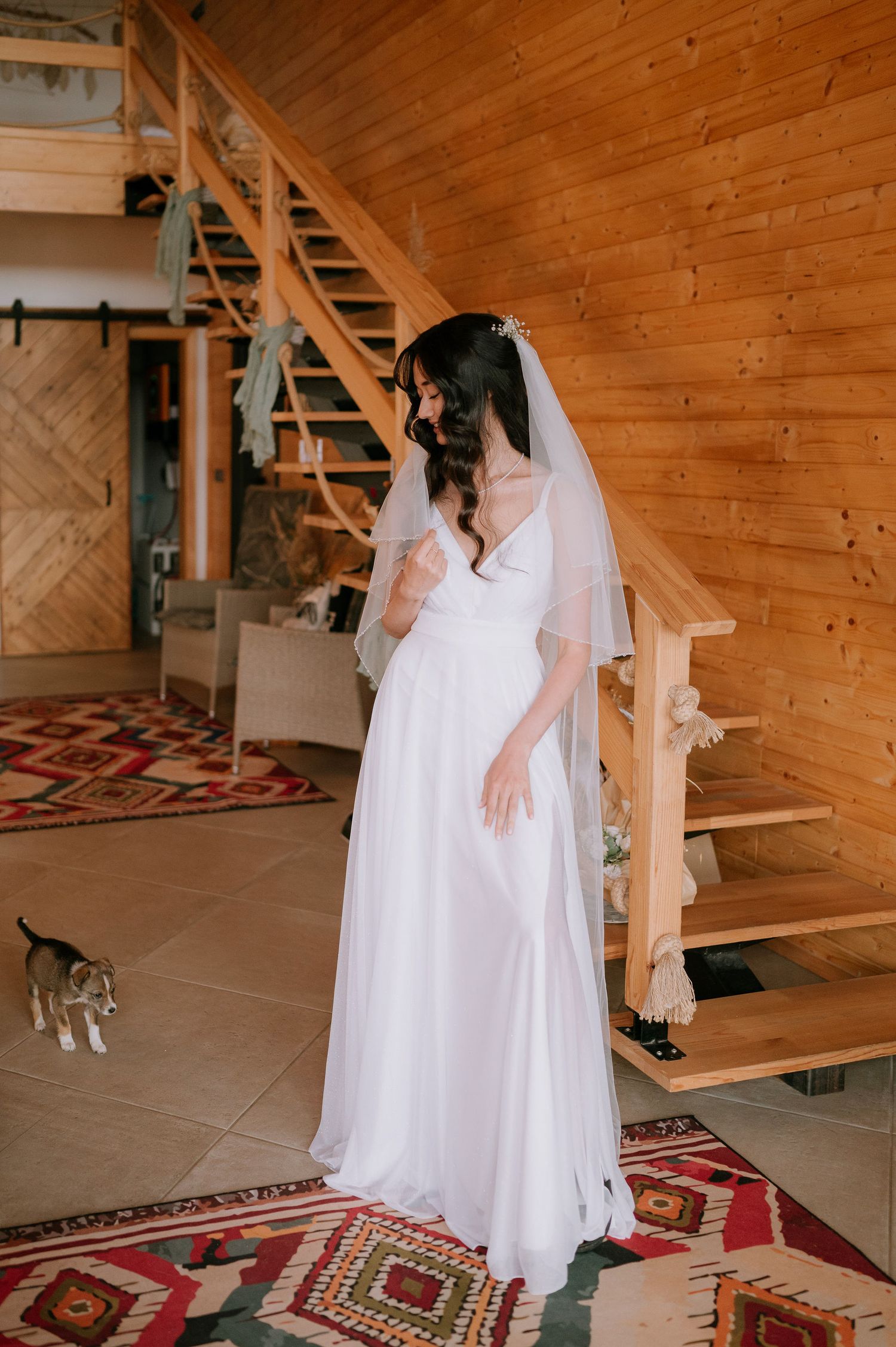 Long white dress flowing in rustic room with wooden walls and decorative rug.