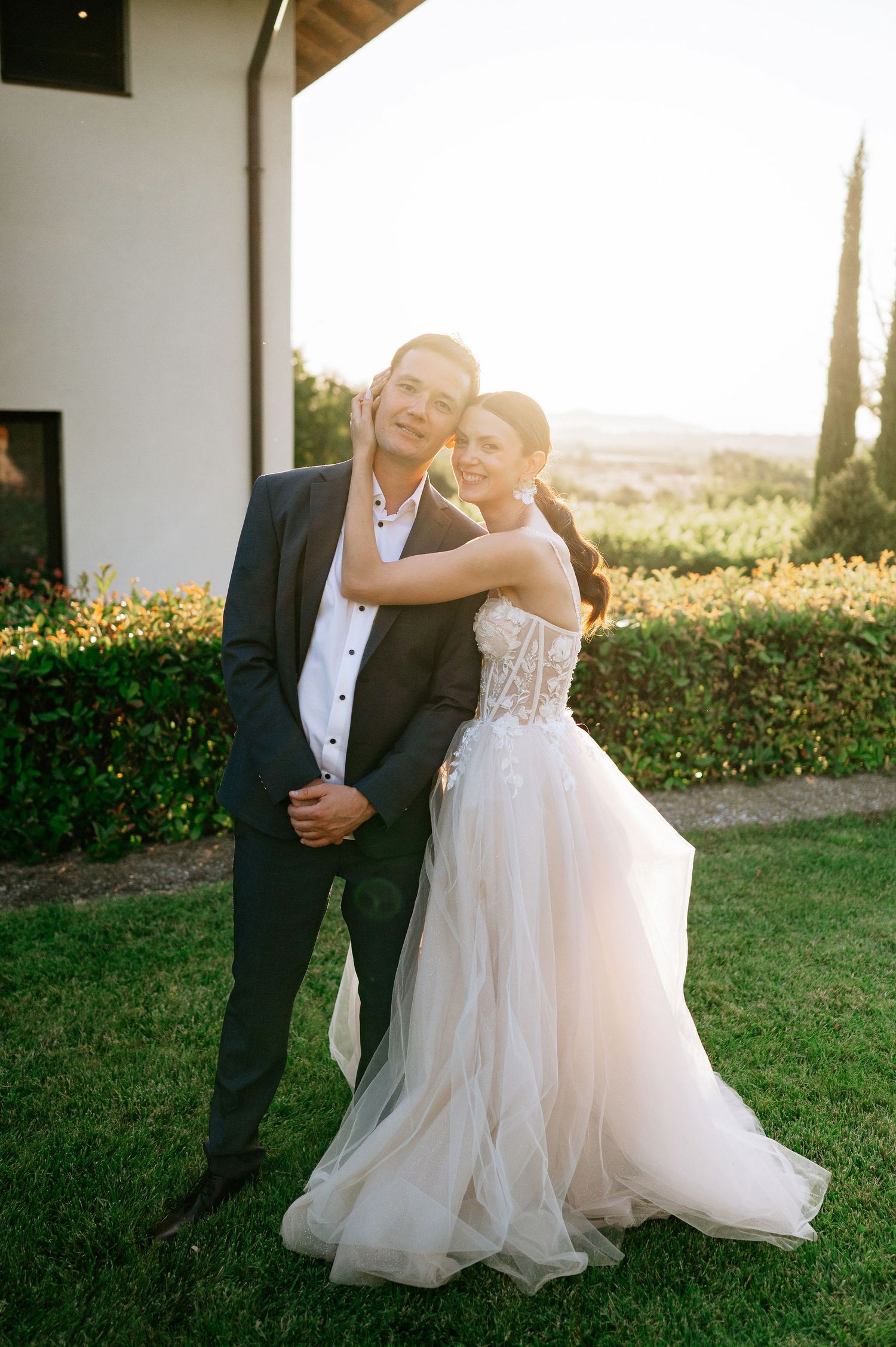 Couple embracing during sunset wedding photos with Mediterranean garden backdrop.