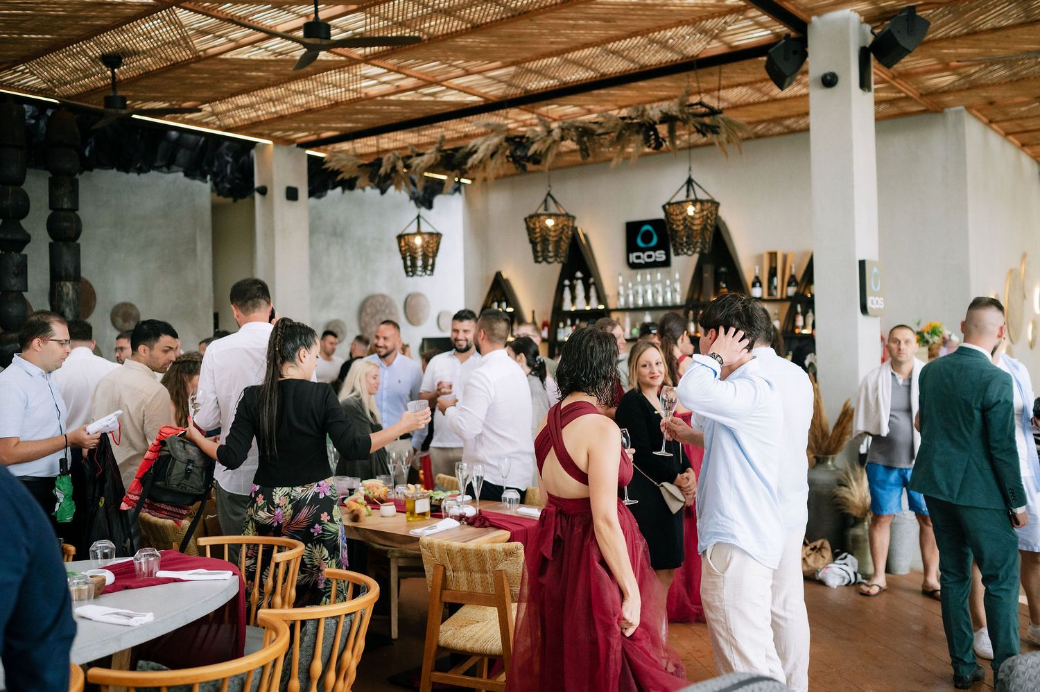 Crowded restaurant interior with guests mingling at tables decorated for a special occasion.