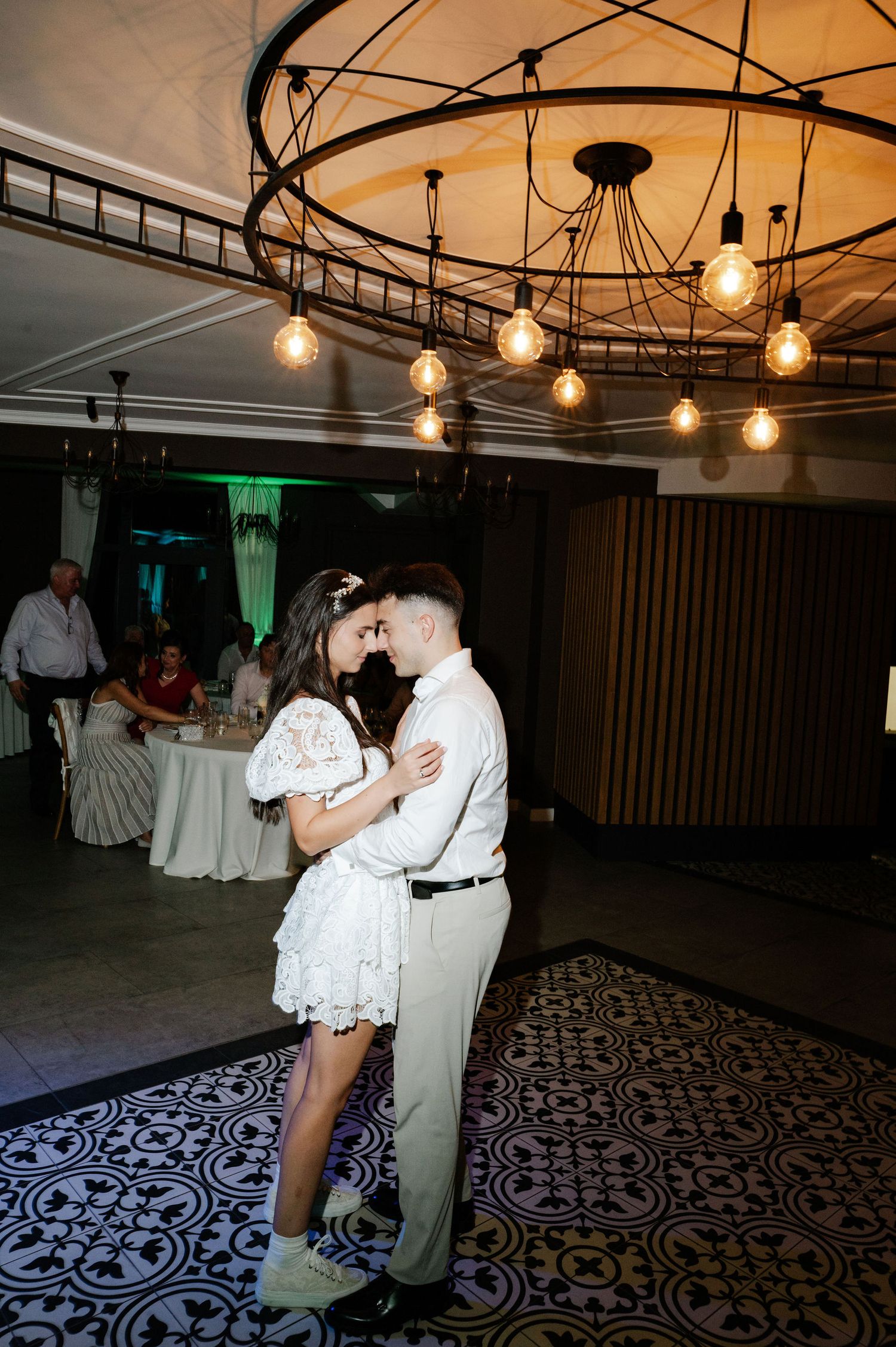 Wedding reception dance floor with decorative patterned carpet and pendant lighting.