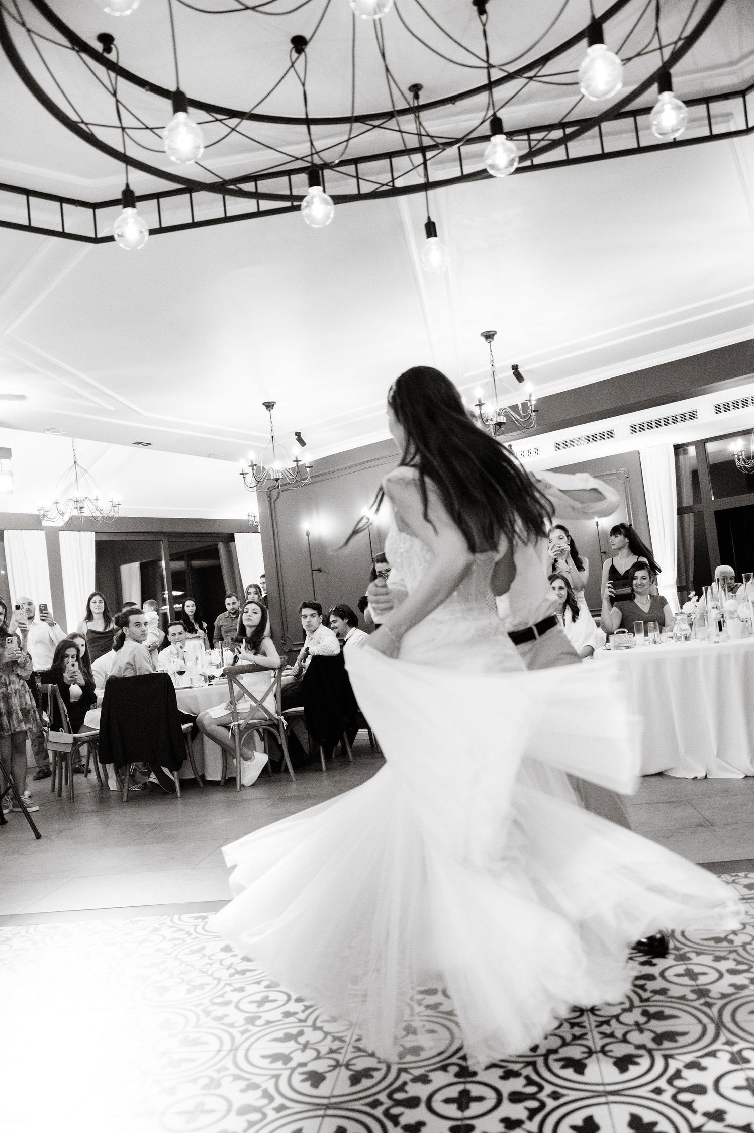 Elegant dance floor with decorative tile pattern and hanging pendant lights in event space.