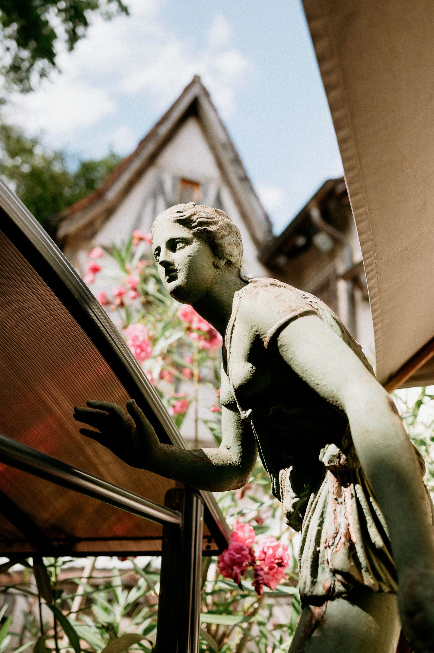 Decorative garden statues framed against pink flowers and traditional architecture.
