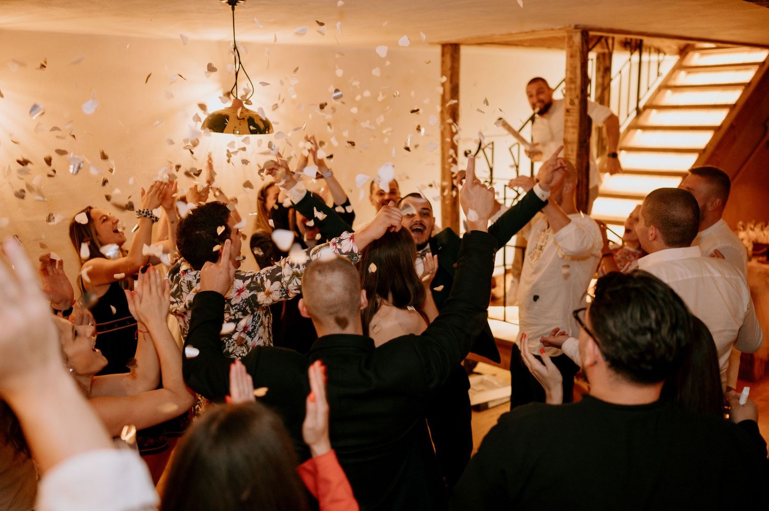 Indoor celebration with confetti falling and guests cheering in a well-lit venue.