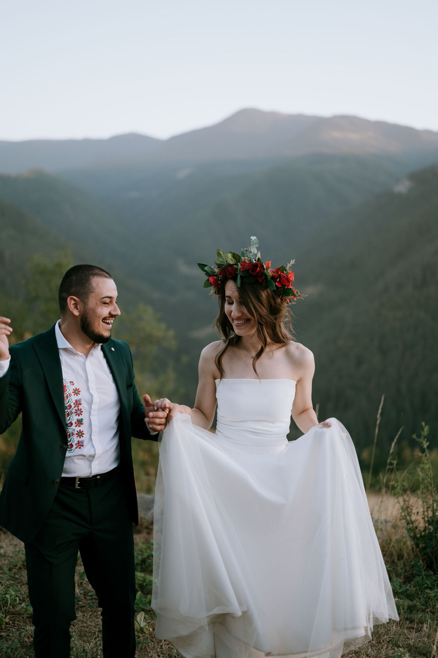 Wedding couple playfully poses in front of mountain ranges during golden hour.