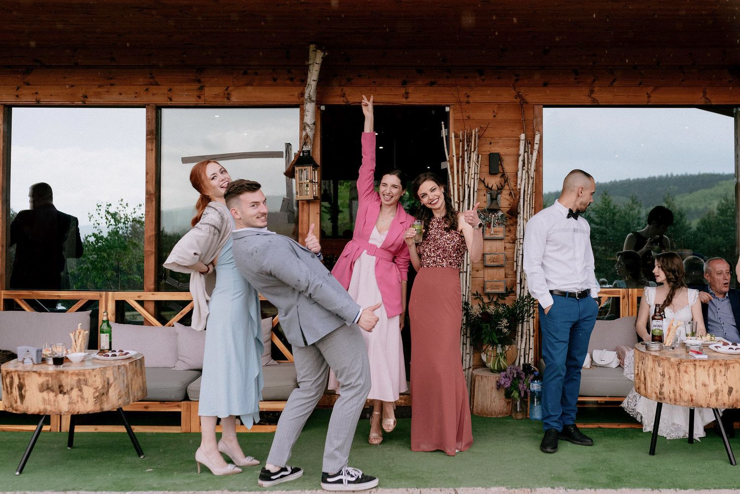 Wedding guests dancing and celebrating on a covered wooden deck with mountain views.