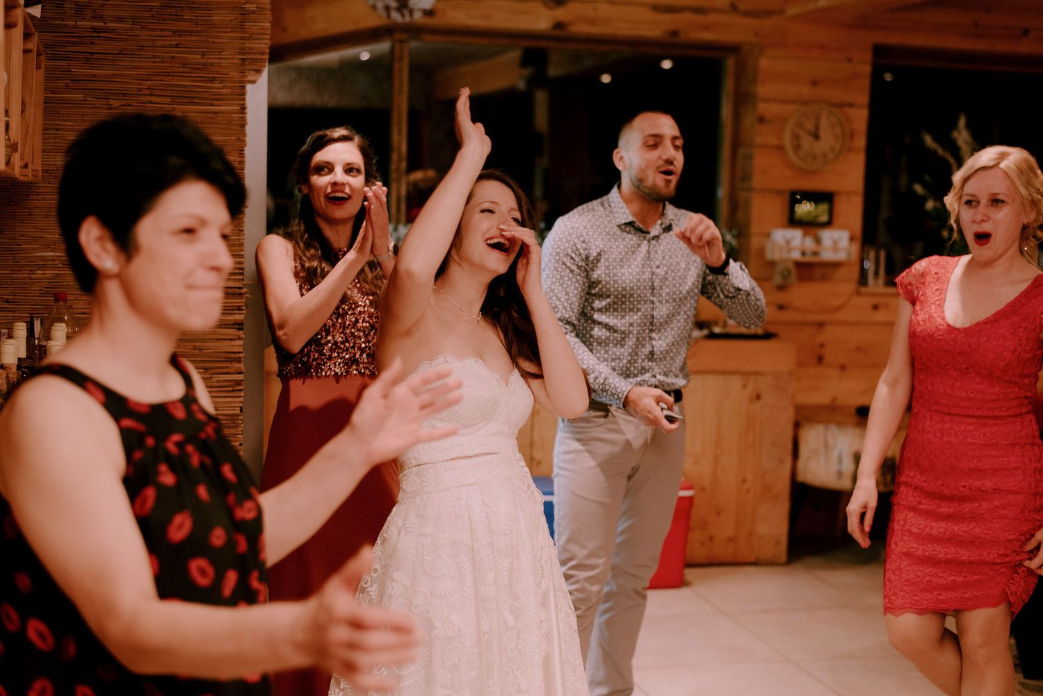 Wedding reception dance party in full swing inside rustic wooden venue.