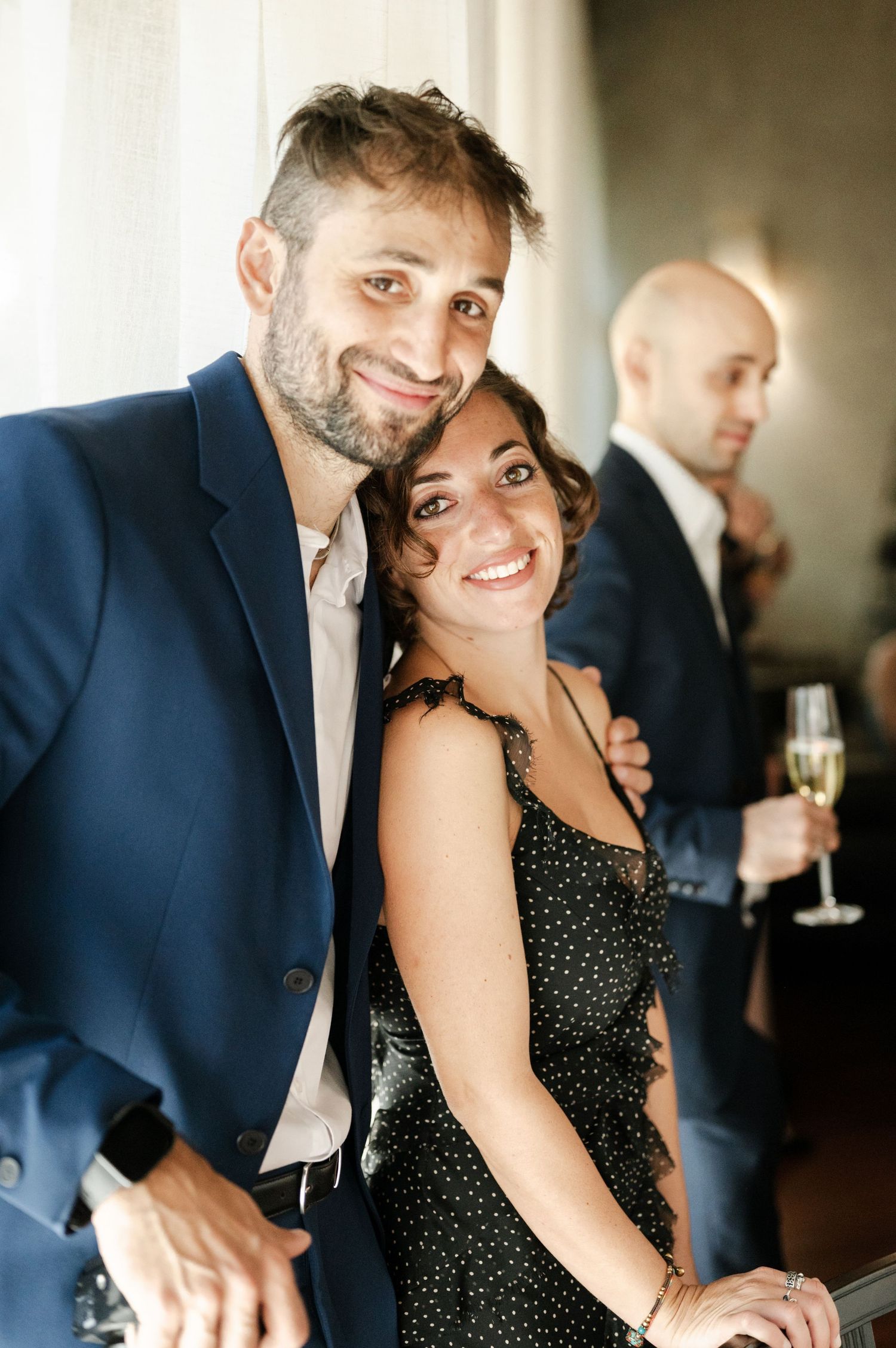 A couple laughs together during a celebration while holding champagne glasses.