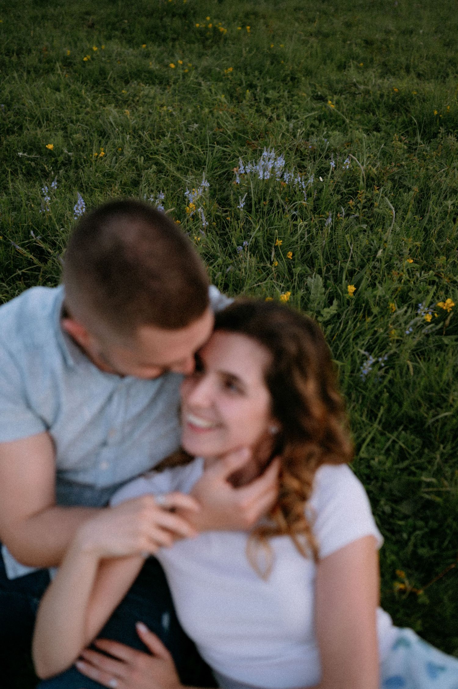 Couple sharing affectionate kisses while relaxing in a spring meadow.
