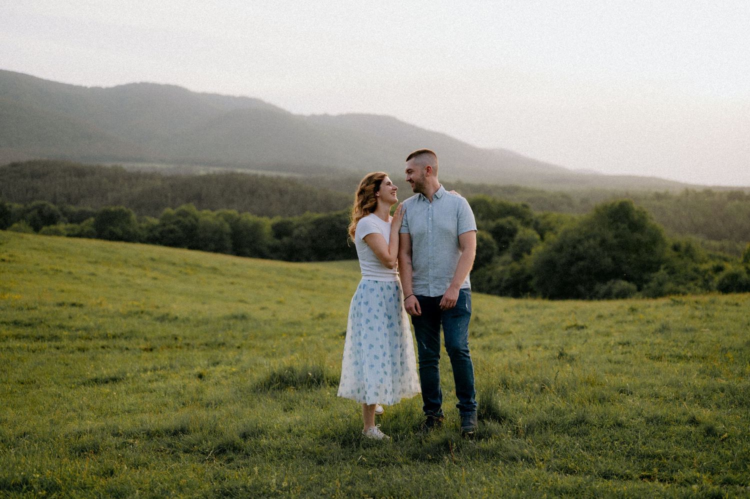 Couple enjoying a romantic moment in a scenic mountain meadow.