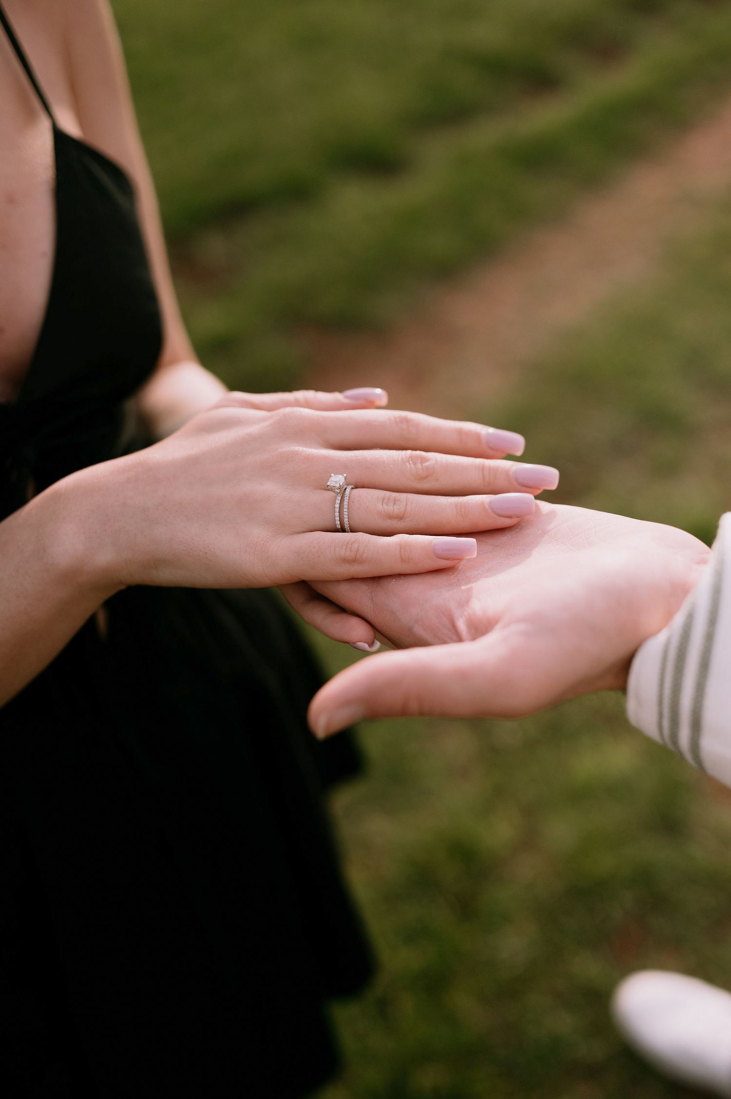 Close-up of hands exchanging rings during a wedding ceremony in an outdoor garden setting.