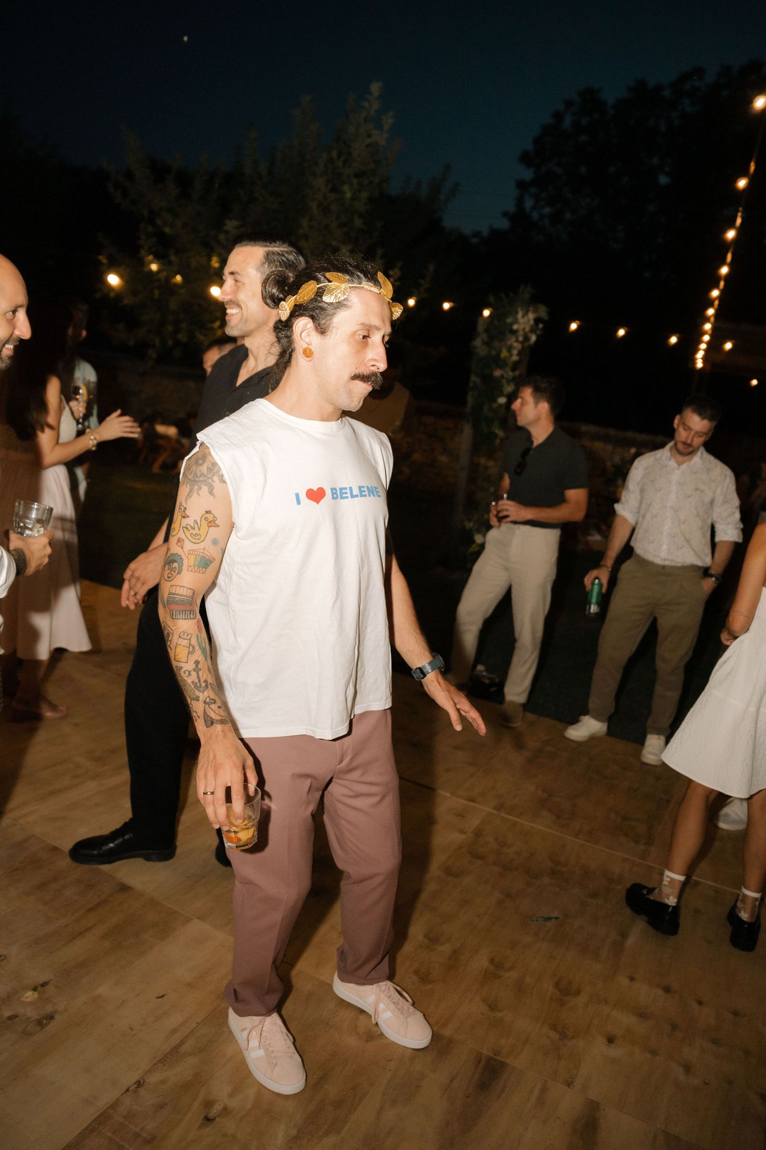 People dancing and having fun at a nighttime outdoor party on a wooden dance floor.