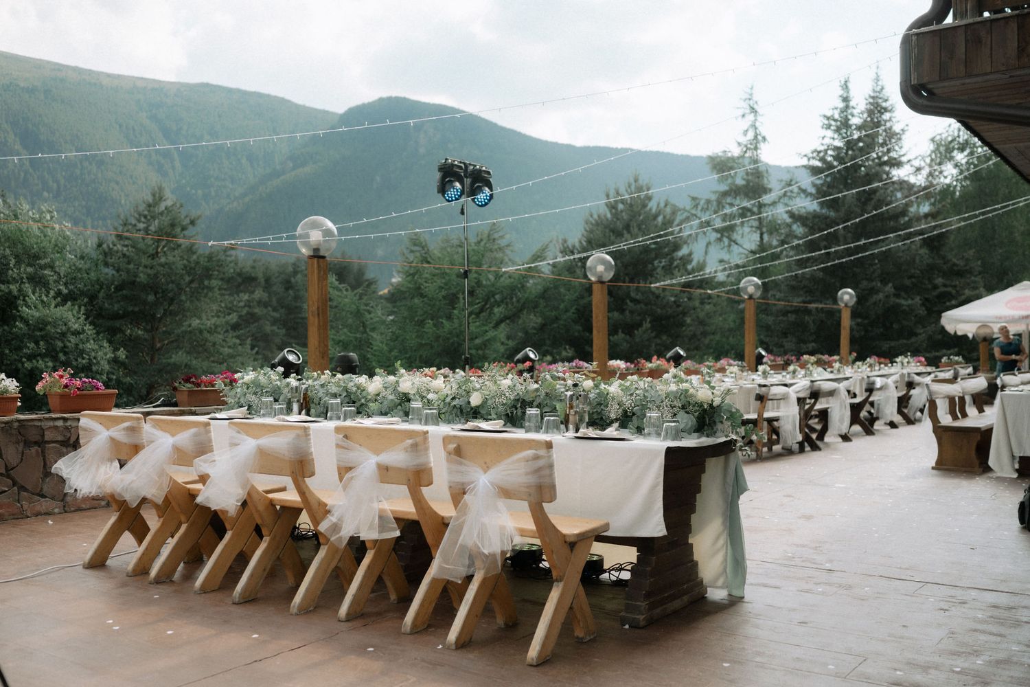 A panoramic view of wooden benches and tables arranged outdoors against a backdrop of misty mountain scenery.