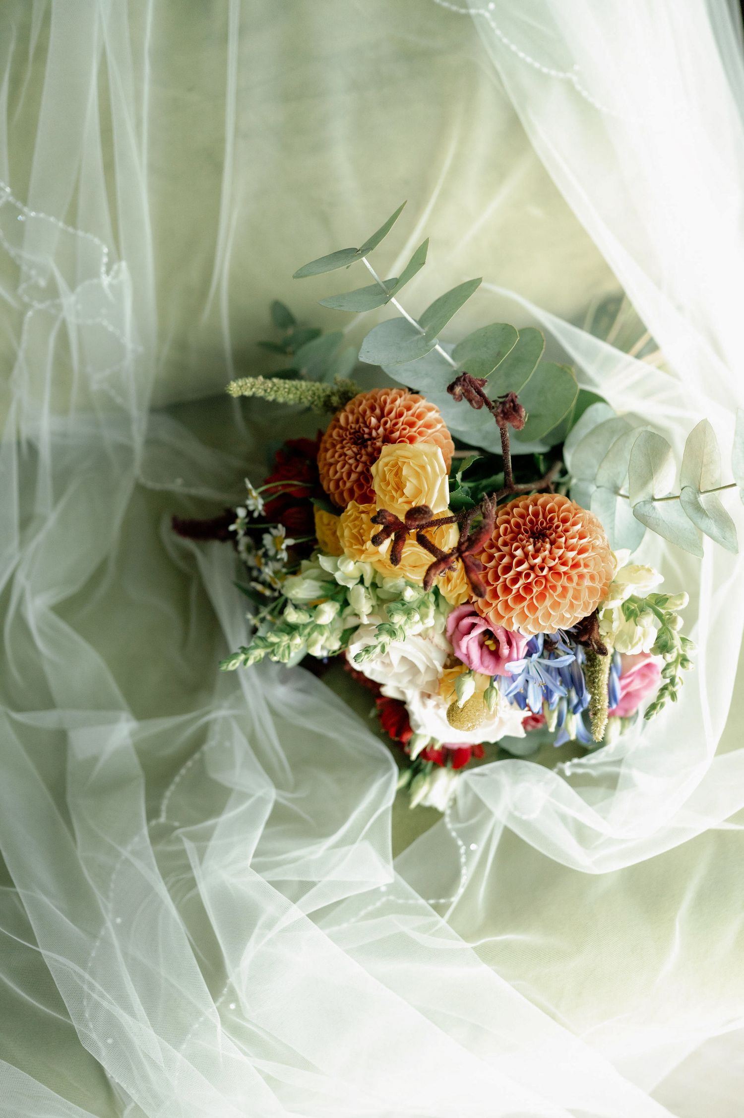 Beautiful floral hair accessories with coral dahlias and mixed blooms nestled in soft white tulle fabric.