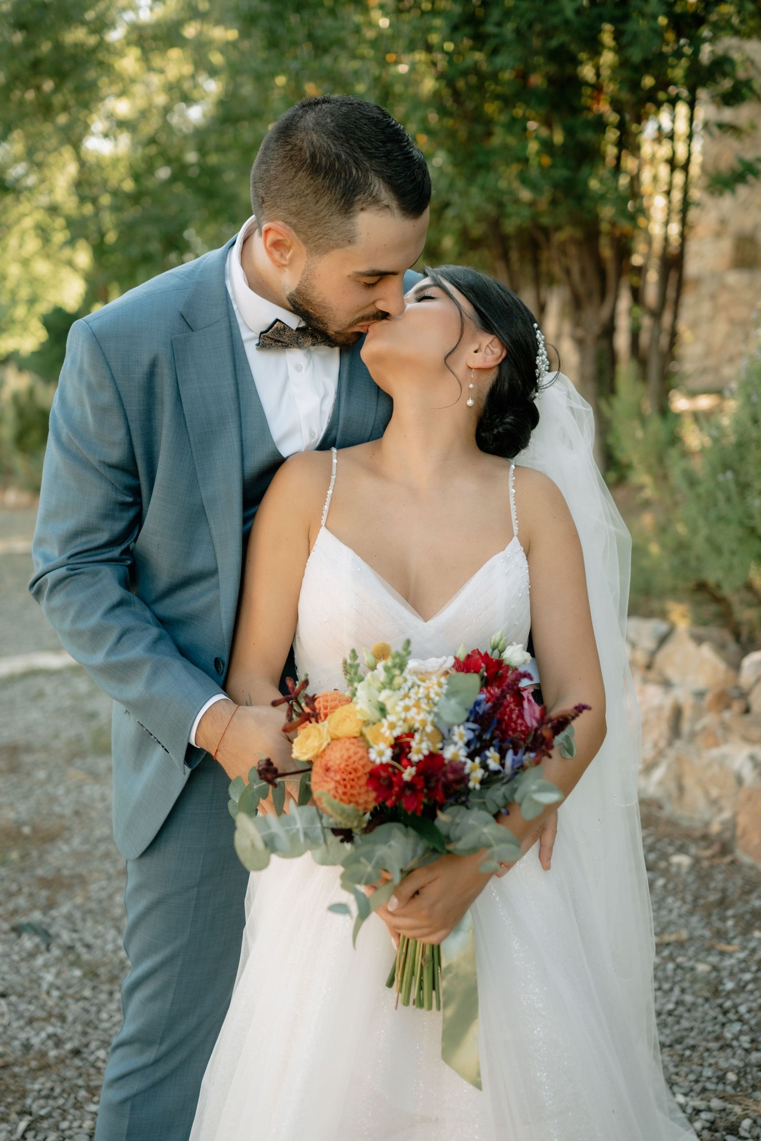 A romantic wedding photo series showing a couple embracing in an outdoor setting with autumn-colored bouquet.