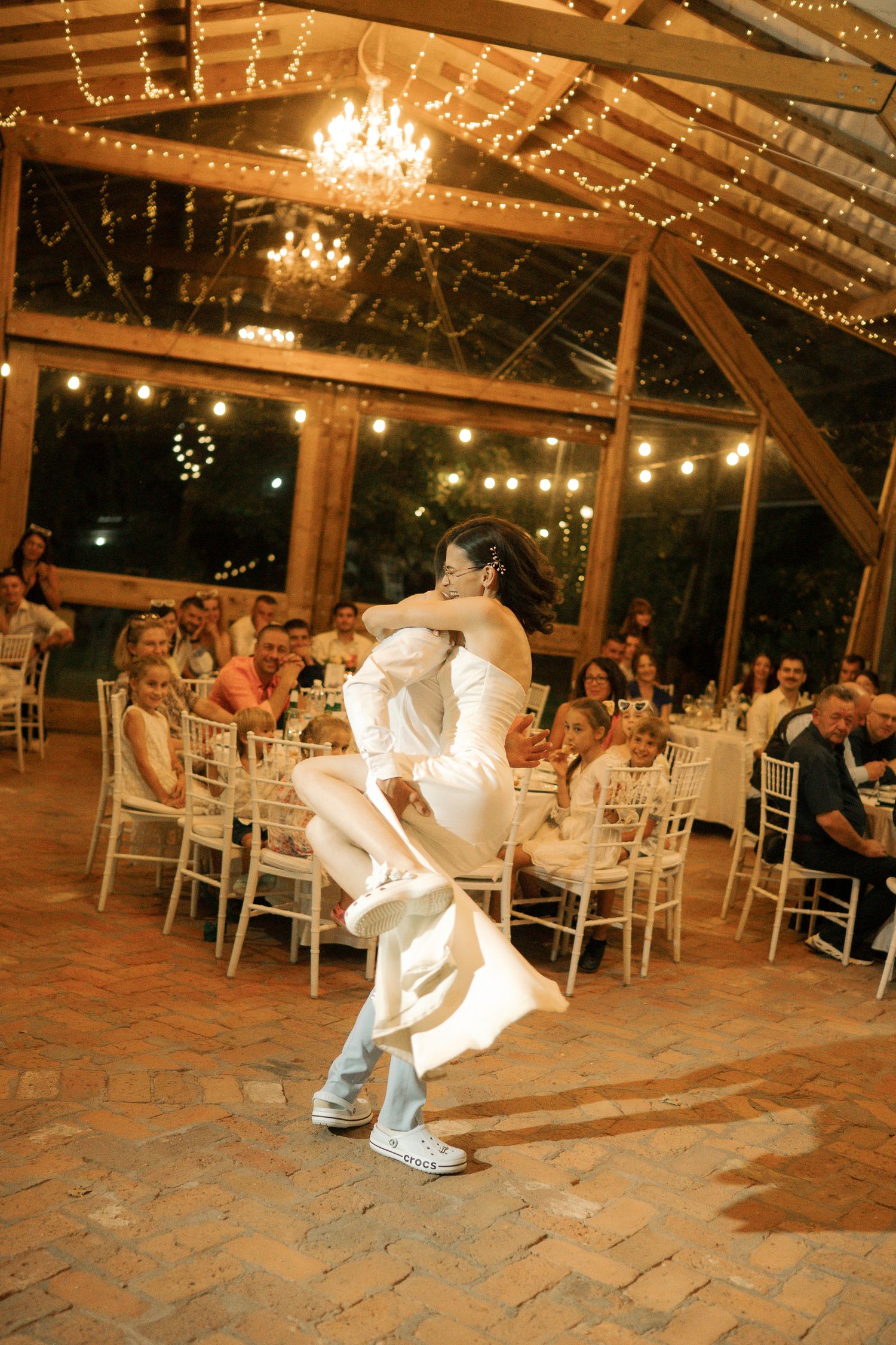 A sequence of dance moves at a wedding reception venue decorated with string lights and chandeliers.