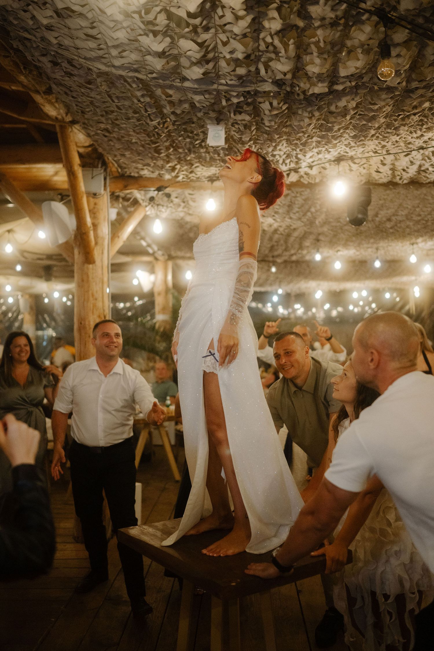 Wedding guests dancing together in a rustic underground cave venue decorated with string lights.