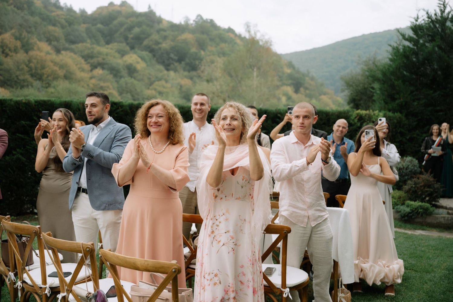Wedding guests enjoy a lively outdoor celebration in a scenic mountain setting with natural greenery and decor.