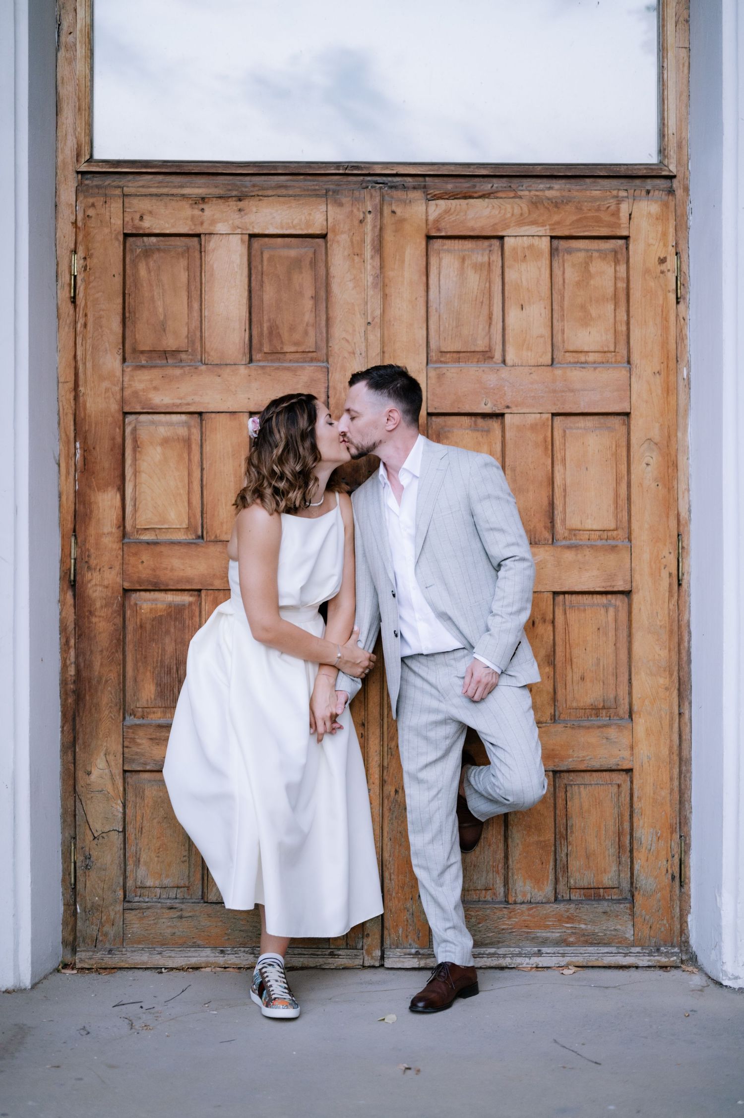 A series of three artistic wedding photos showing a couple posing playfully against wooden church doors.